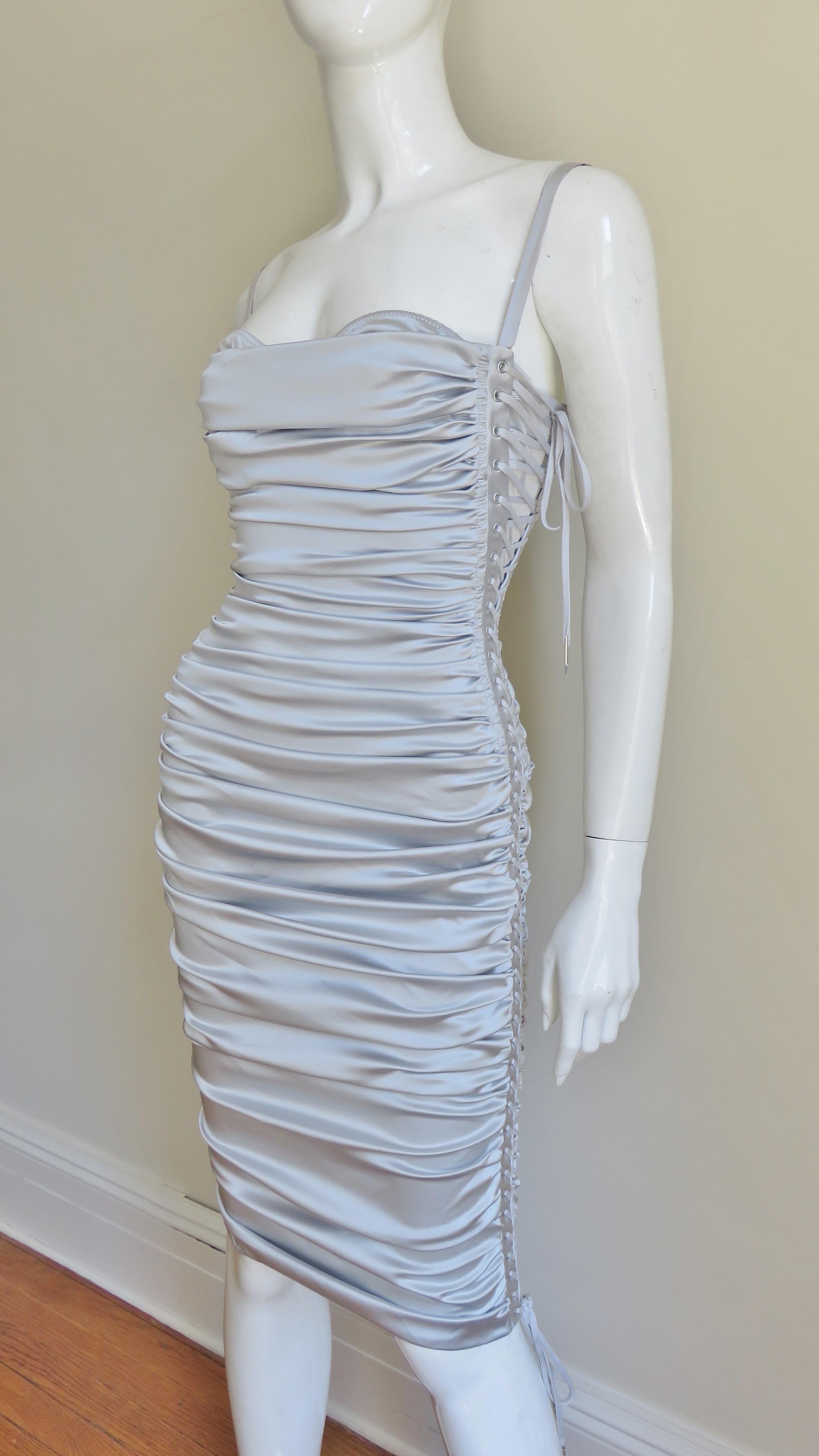 A fabulous silver grey stretch silk bodycon dress from Dolce and Gabbana.  It is horizontally ruched across the body the length of the dress with adjustable lacing along the side.  It has an attached matching silk bra with adjustable straps that