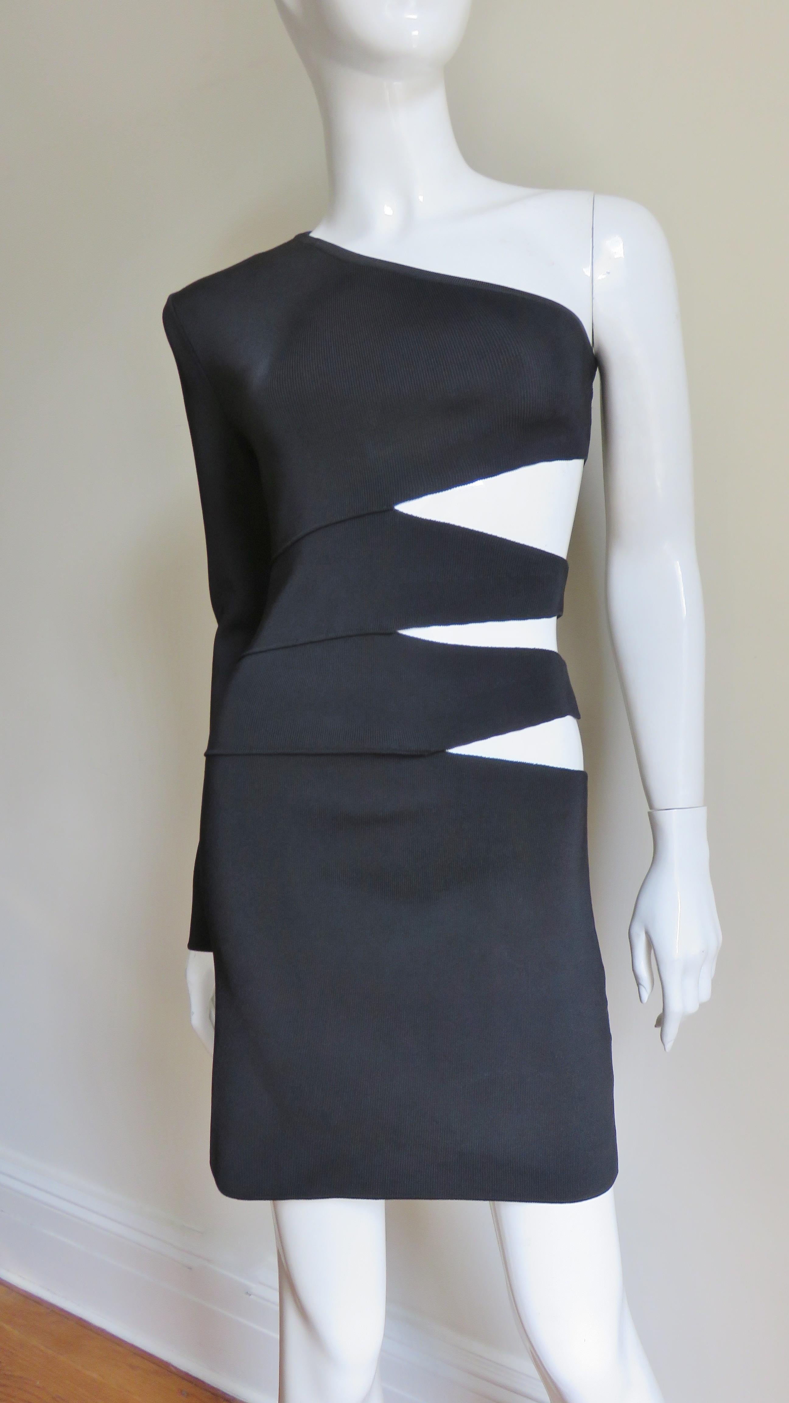 A fabulous black bodycon bandage dress from Pierre Balmain.  It has one sleeve and a series of diamond shaped cut outs from under the bust  to the hips on one side. The skirt is straight and the dress goes on over the head.
Appears unworn.  Fits