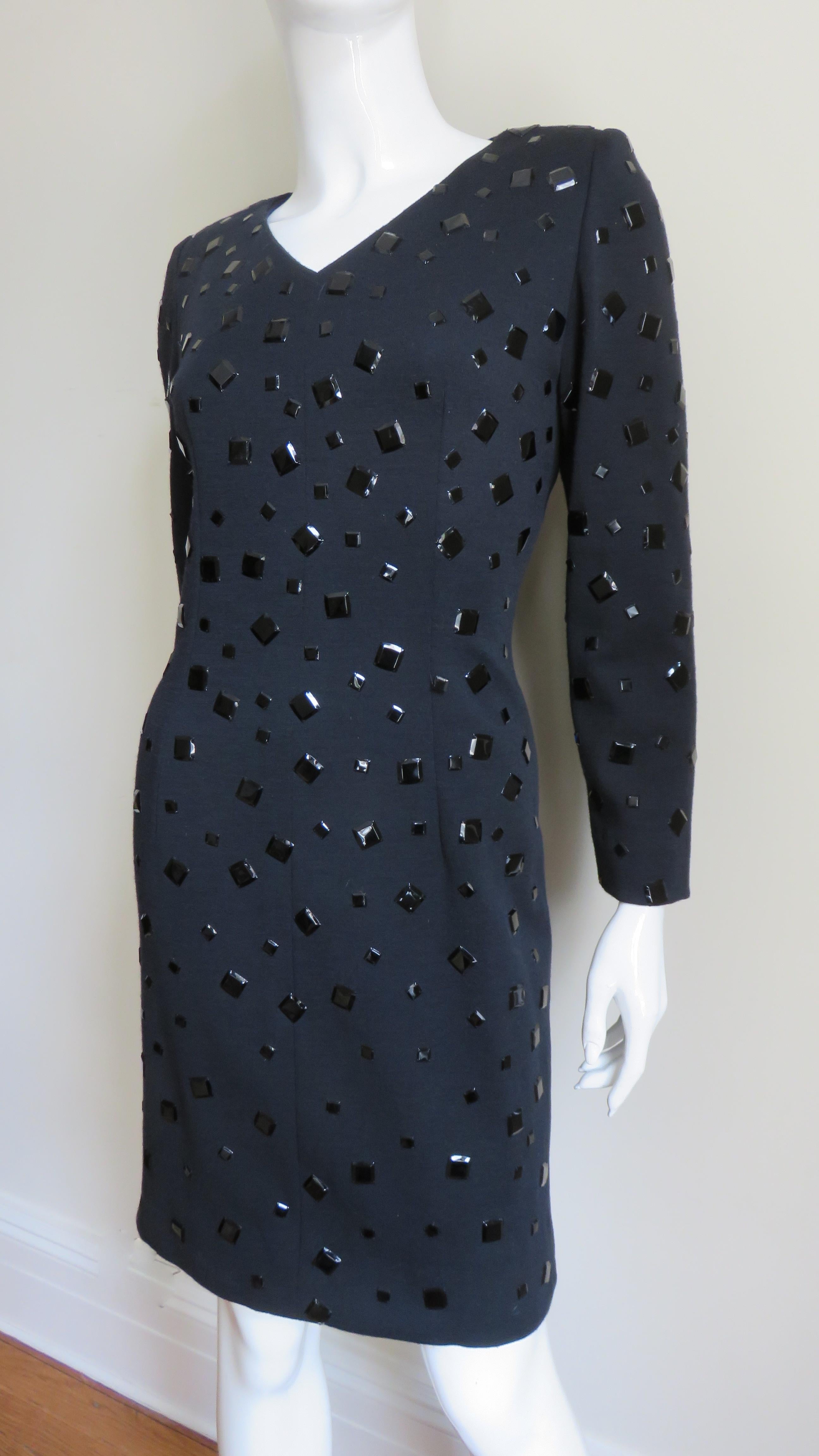 A fabulous wool jersey dress by Givenchy.  It is semi fitted with a small V neckline, long sleeves and lightly padded shoulders. The entire dress is covered in shiny black metal squares of varying sizes.  It is lined in black silk and has a hand