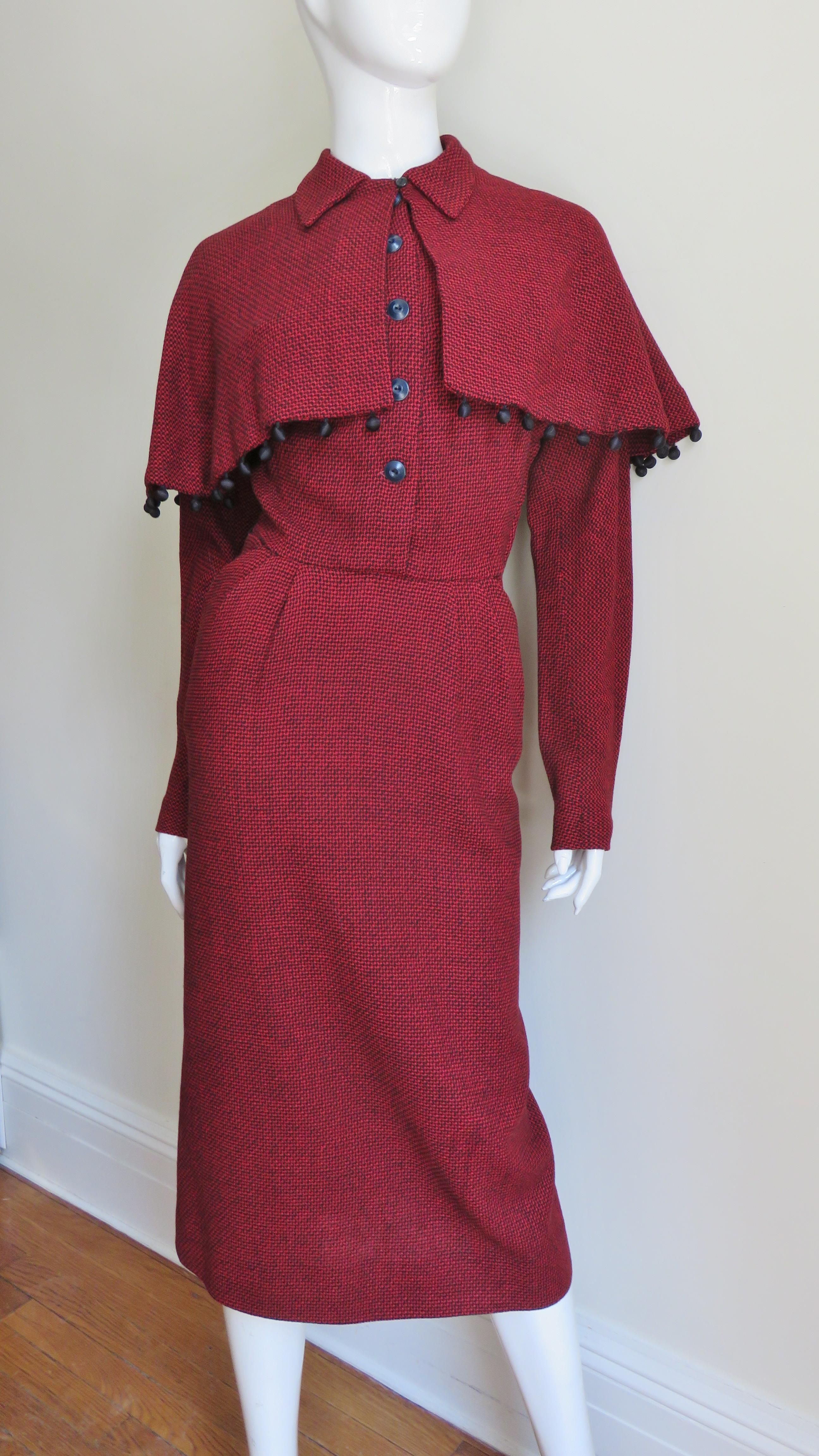 A fabulous black and red wool small hounds tooth pattern dress with a detachable cape.  It has a peter pan collar, button closure to the waist and raglan cut sleeves.  The skirt portion has 2 tucks on either side of the center front waist, 2