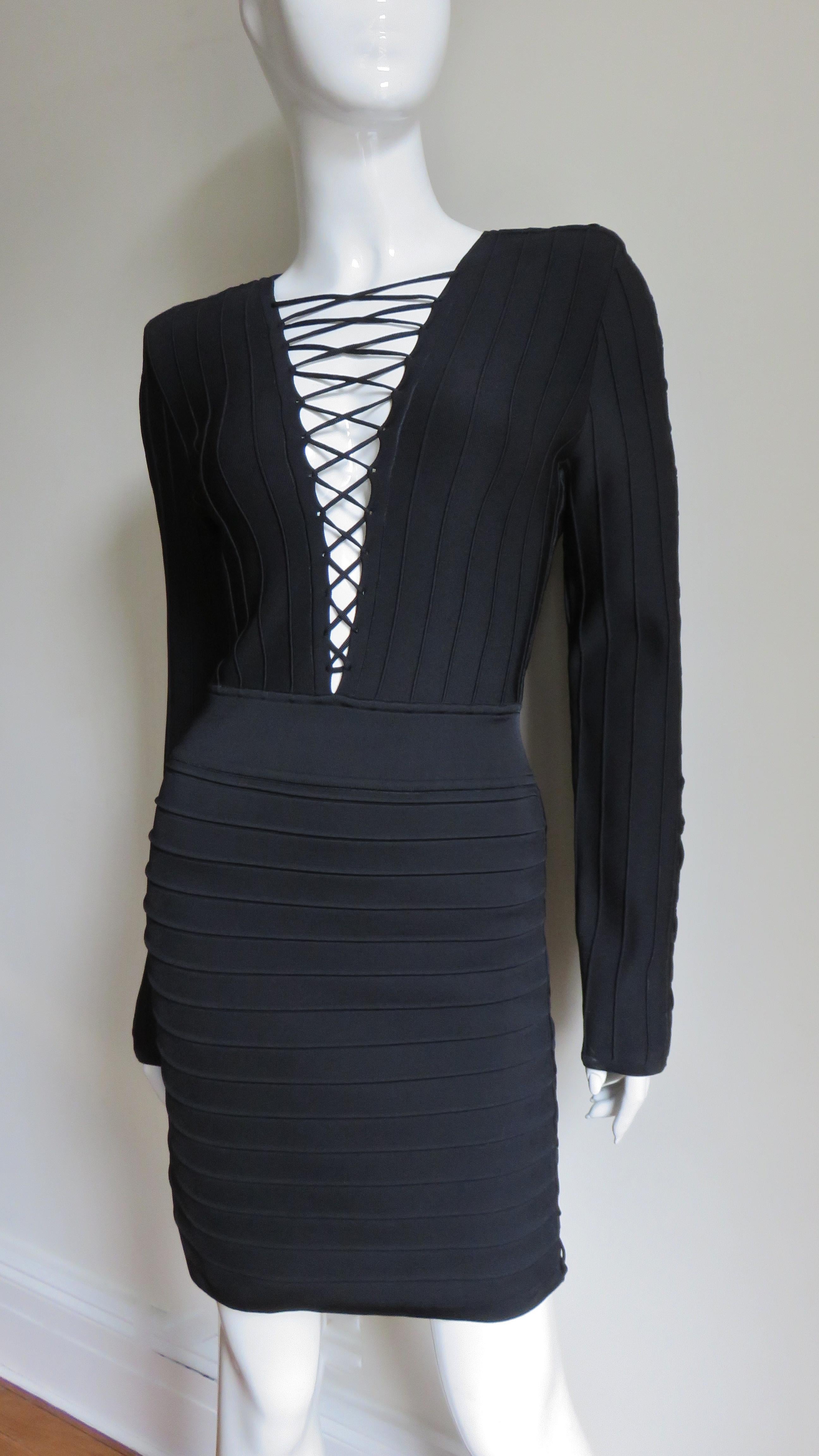 A fabulous black bandage dress from Pierre Balmain.  It is fitted and has a plunging front neckline with adjustable lacing through to the waist.  There is lacing along the tops of the shoulders and sleeves to the wrists and from underarm to waist. 