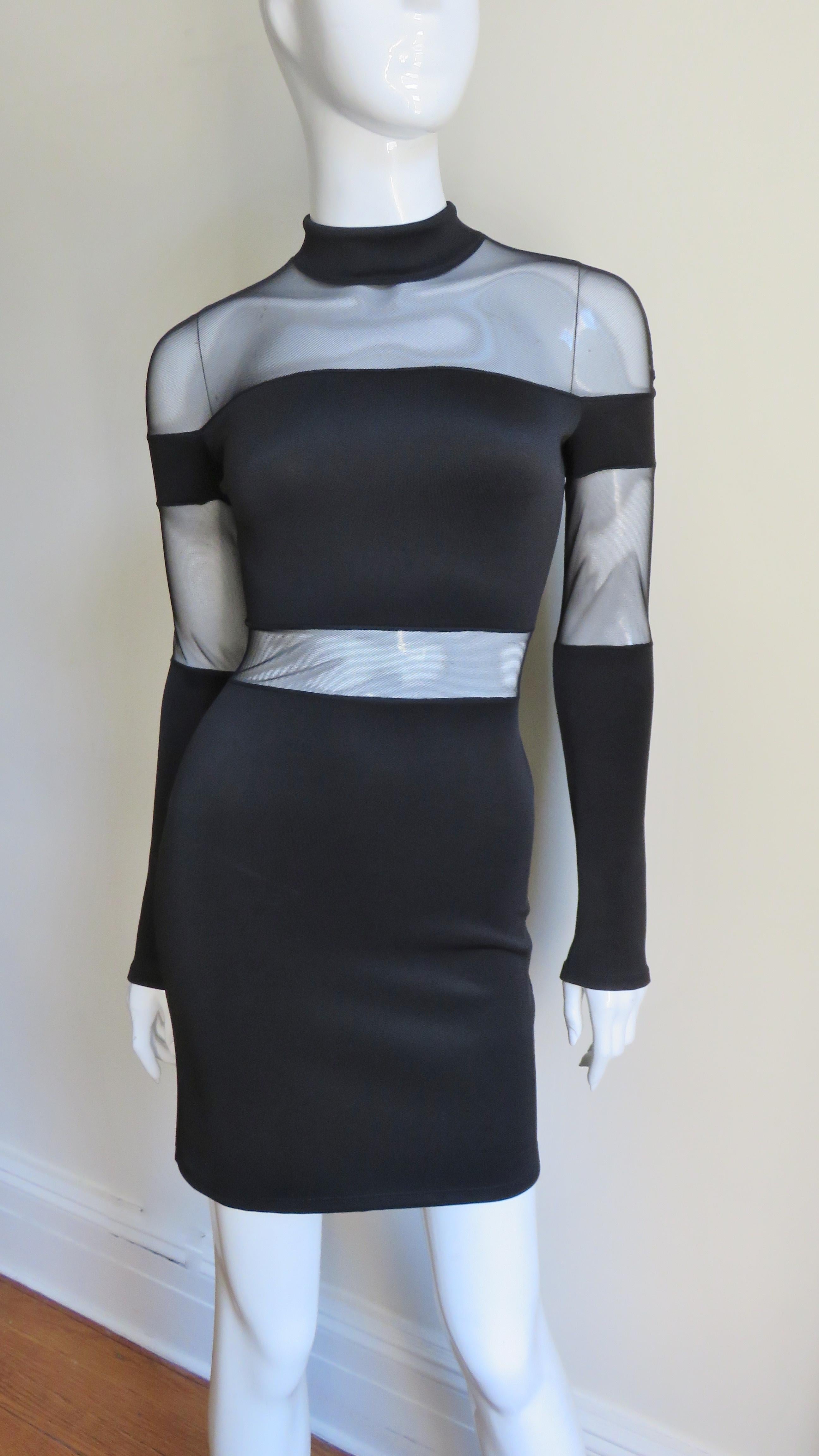 A gorgeous black bandage dress from Pierre Balmain. It has a stand up collar, long sleeves and is fitted through to the hips. There are fabulous horizontal sheer panels around the shoulders, upper arms and waist.  Very dramatic.  It closes with a