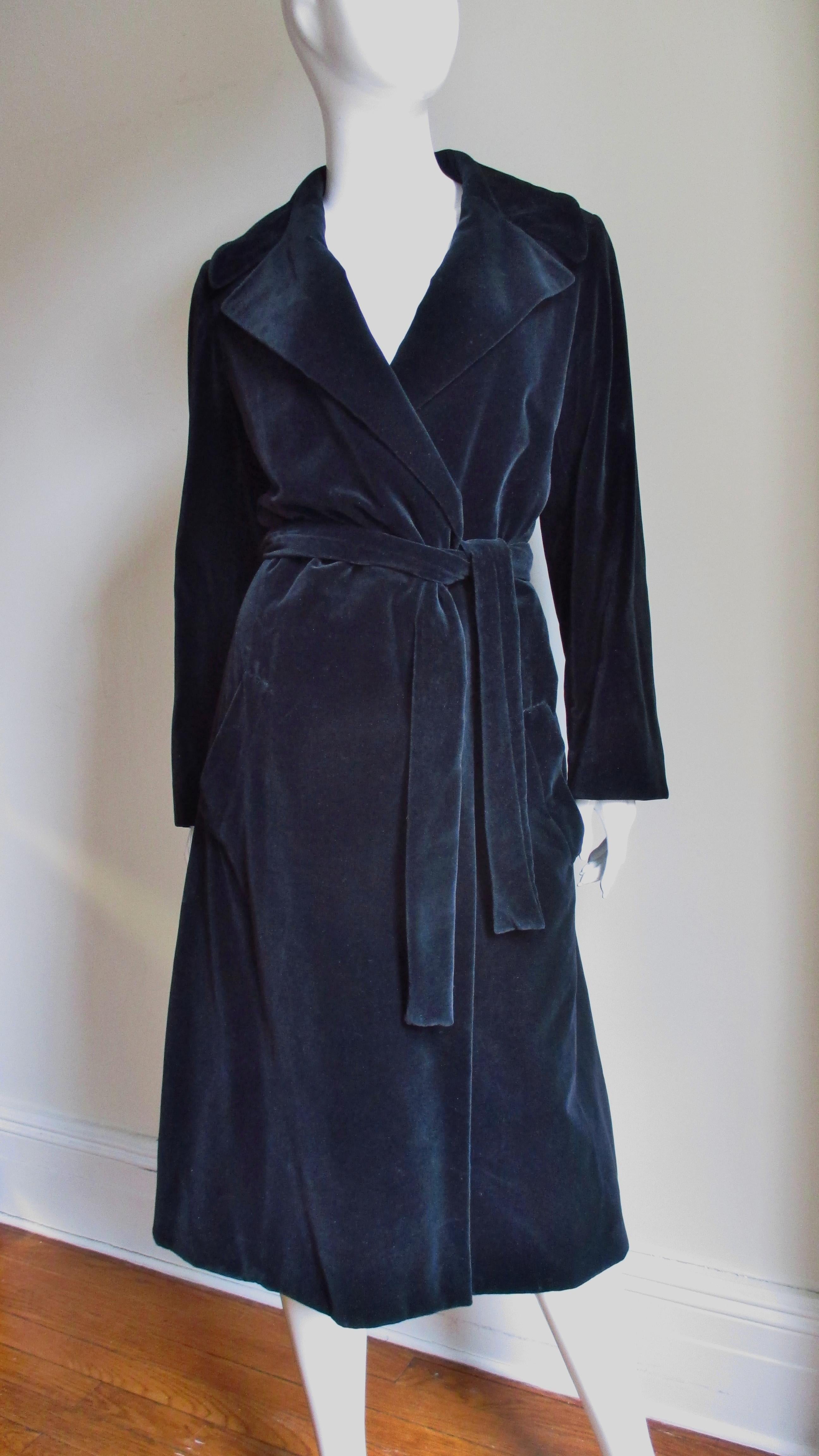 A fabulous example of 1970's Halston in this black velvet wrap trench coat.  It has a large notched collar, hip pockets and wraps tying closed with a matching belt.  It is fully lined in black silk and has 2 slant front pockets. 
Fits Small, Medium,