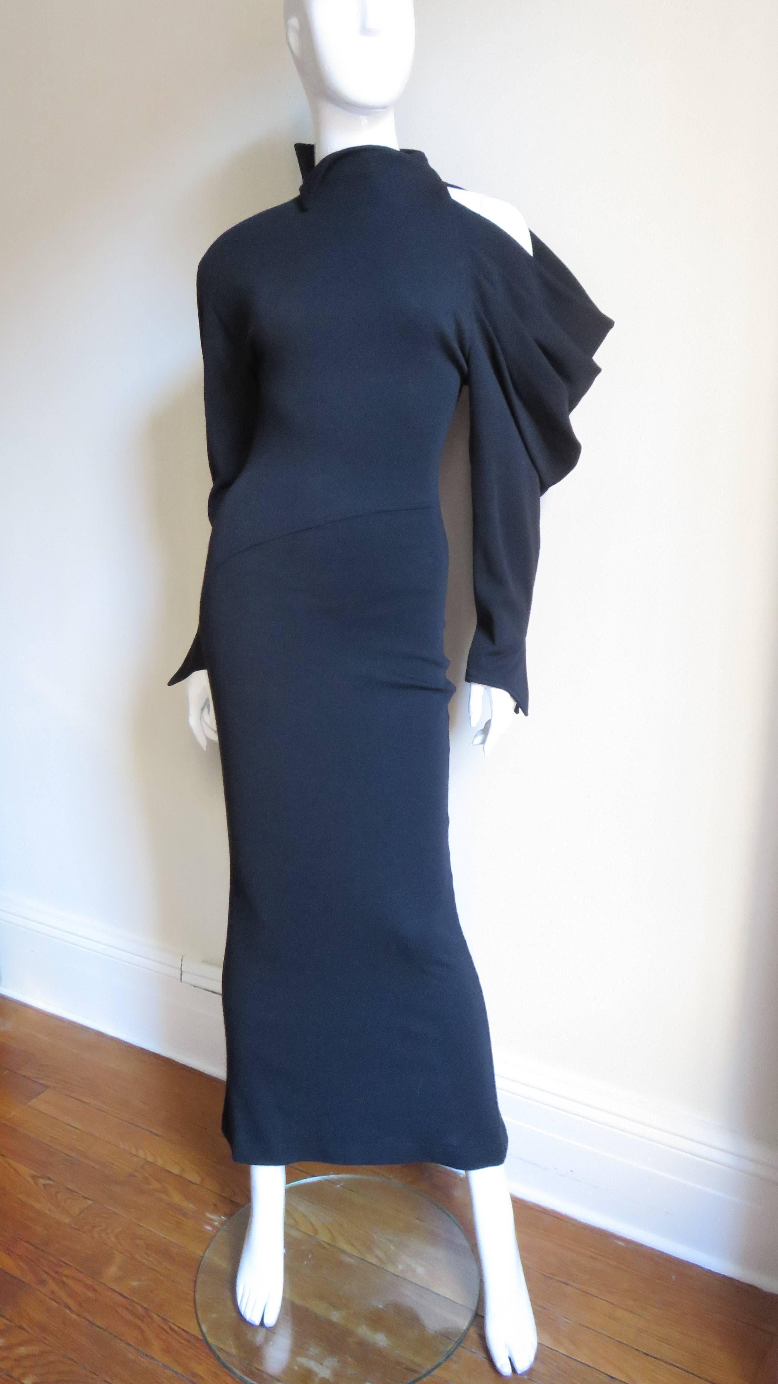 A dramatic long black wool jersey dress from Claude Montana.  It is fitted, enhanced with diagonal seaming flaring slightly at the hem. It has pointed split cuffs and a stand up collar. The drama comes from the sleeves - one ordinary long fitted