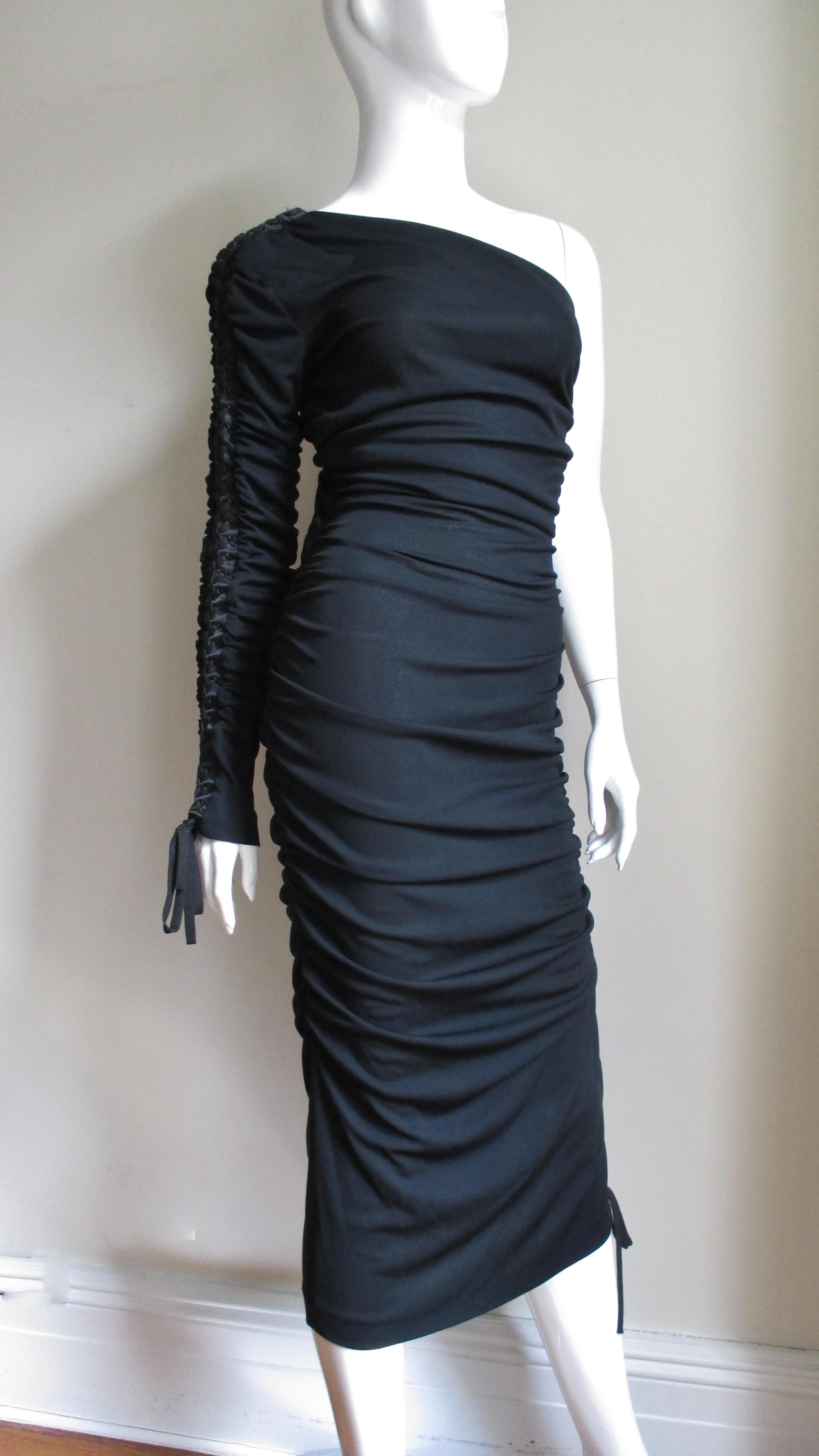 A fabulous black silk jersey dress from Dolce & Gabbana. The fitted dress has one sleeve and intricate functional adjustable lacing along the top of the sleeve from wrist to shoulder and along the length of opposite side of the dress creating