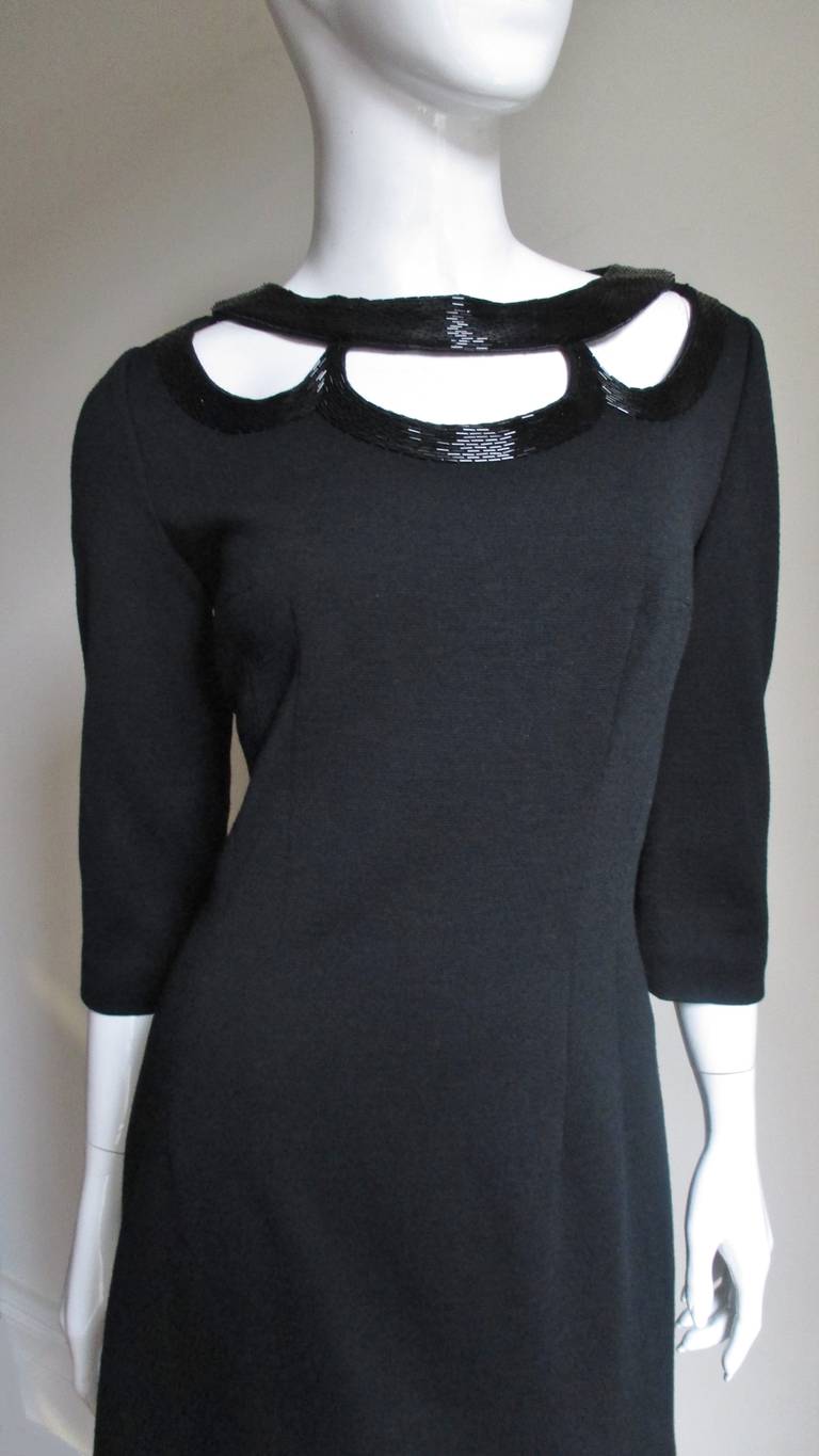 A great black wool jersey dress with a twist by Miss Ruth from British Hong Kong.  It has rows of black glass tubular beads surrounding crescent shaped cut outs around the neck front and back. The dress is semi fitted, nipped in at the waist and has