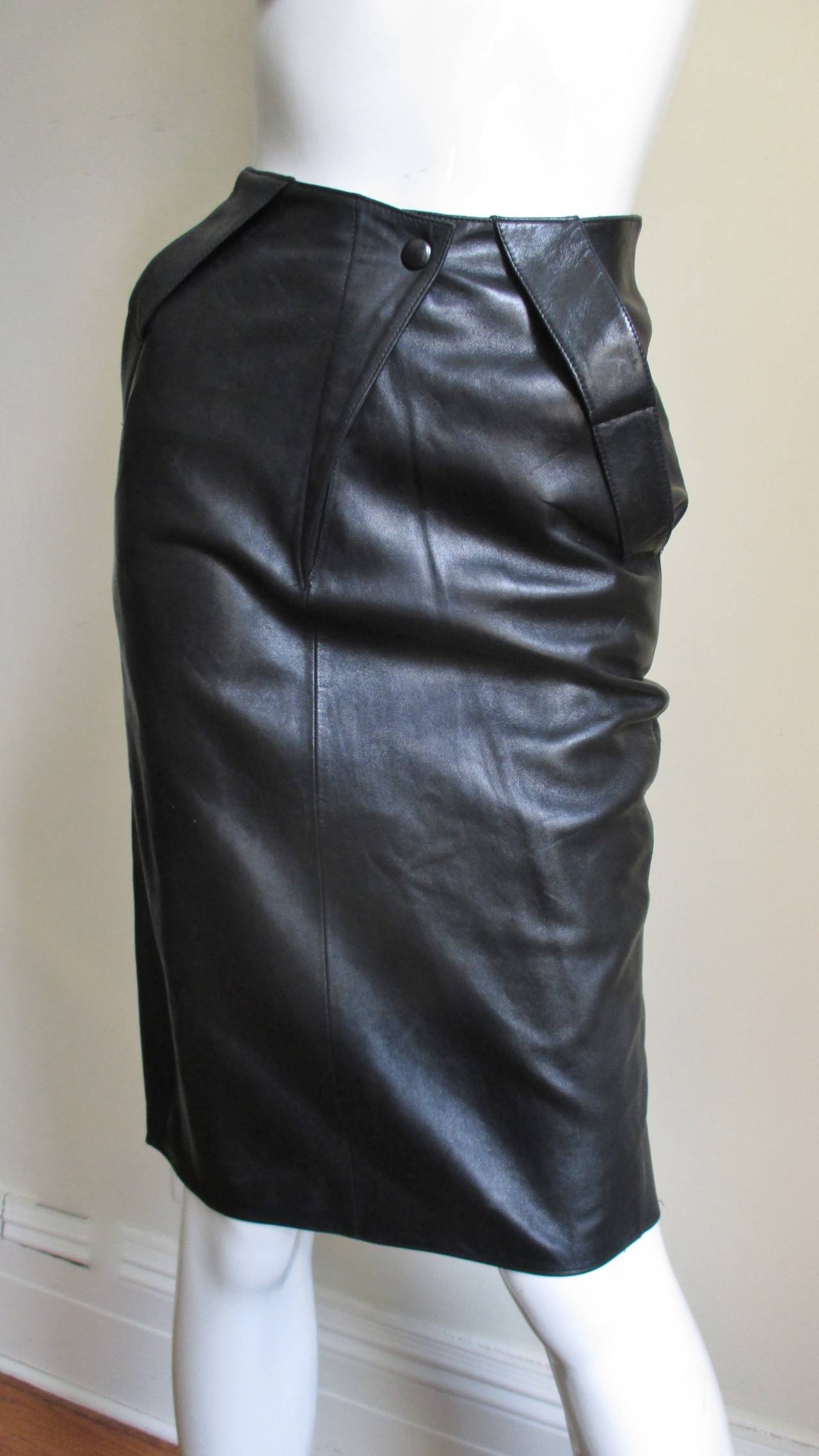 A fabulous black leather skirt from Claude Montana with a back drape.  It is form fitting with a with center front zipper and a black snap and 2 hip pockets.  The back has an incredible dramatic folded draped curved inset at the derriere and it is
