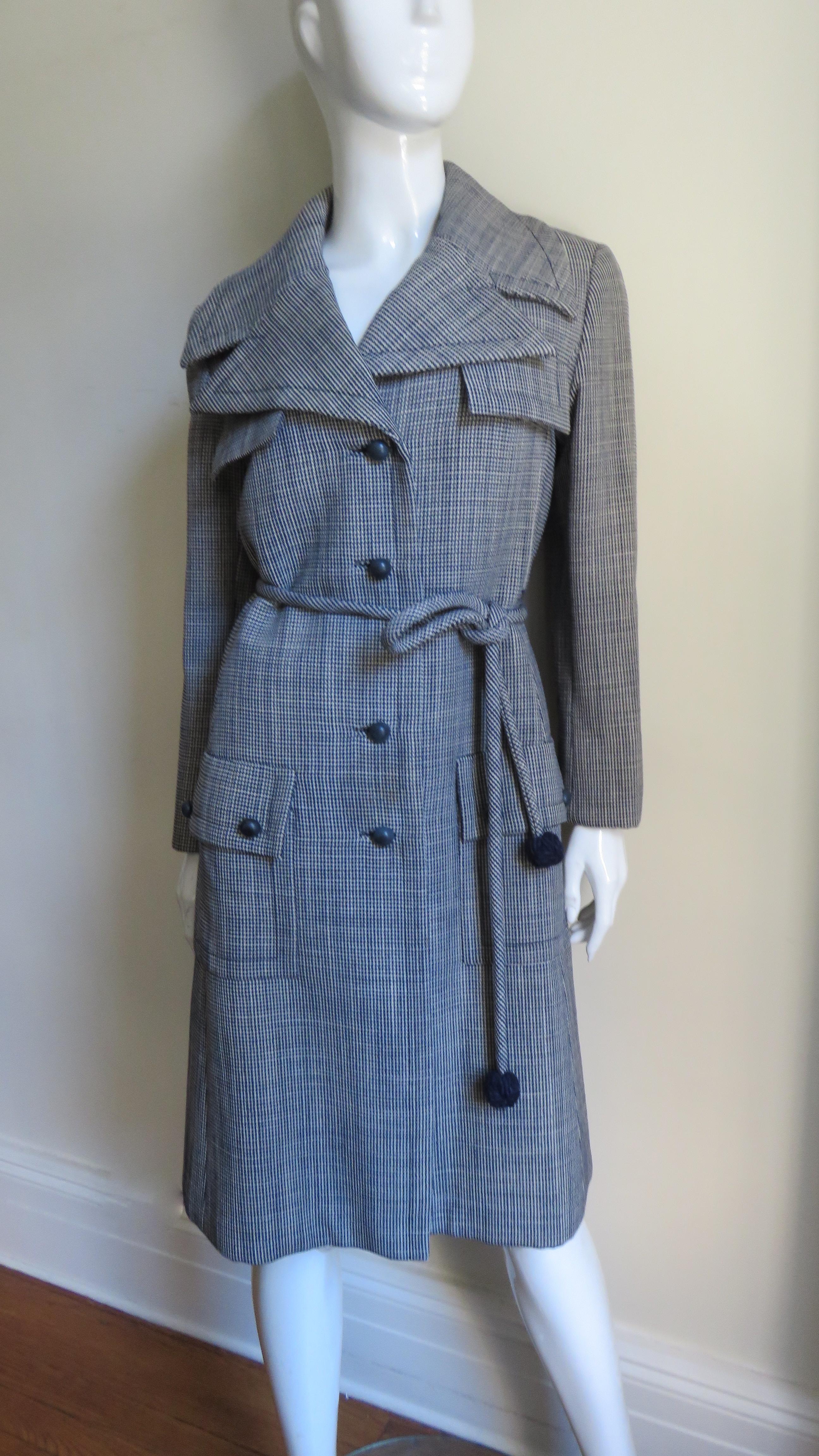 A beautiful off white and navy wool fine hounds tooth print wool coat by Christian Dior.  It has a lapel collar, princess seaming for a great flattering fit and 2 front button flap patch pockets at the hips, 2 at the chest. The coat closes in front
