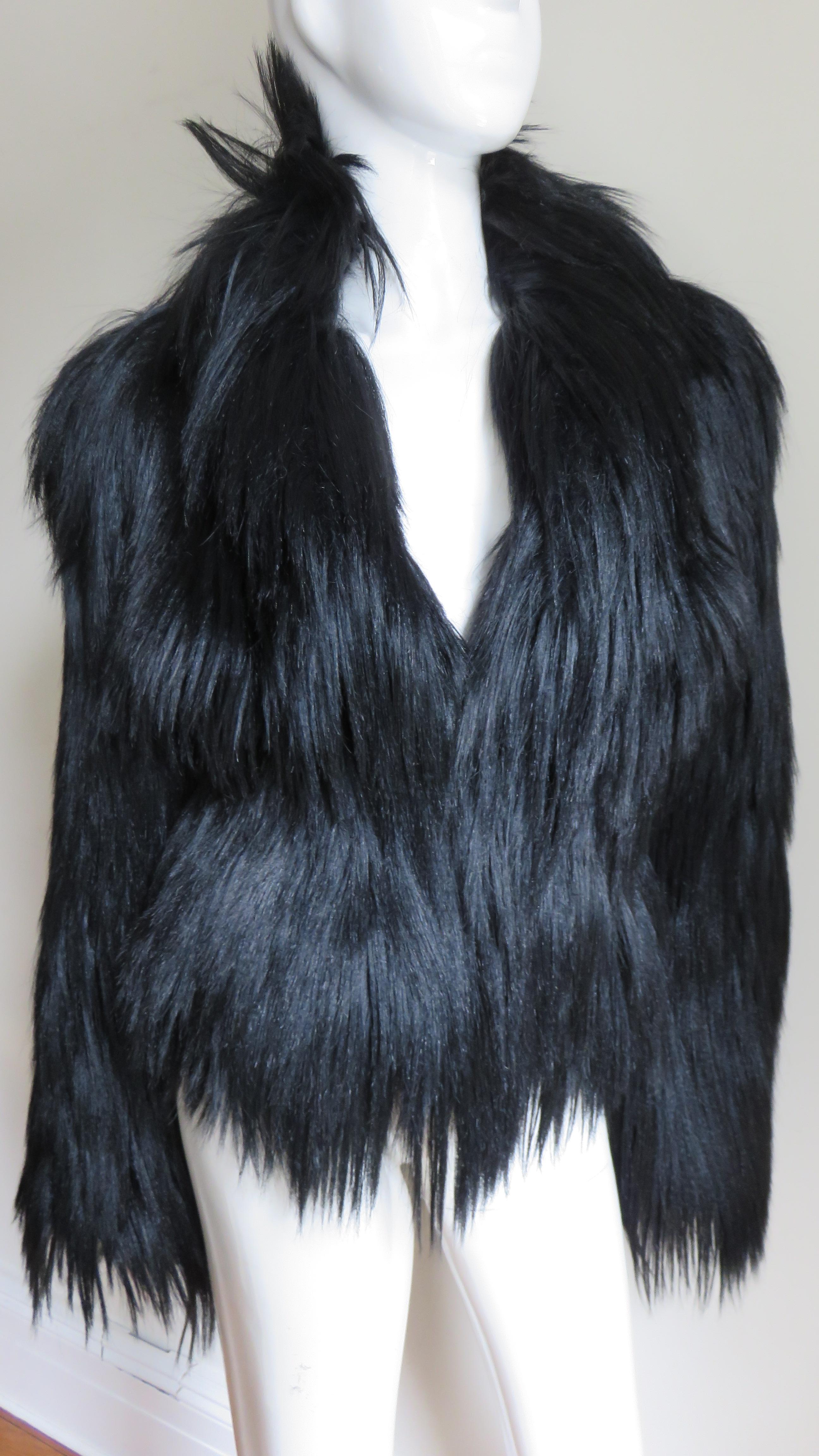 An incredible rare black, shiny, soft, silky goat fur jacket from Alexander McQueen's F/W 2000 Eshu collection. It has a standup collar, V neckline, front fur hook closures and is lined in black silk.  The entire jacket has long silky black fur