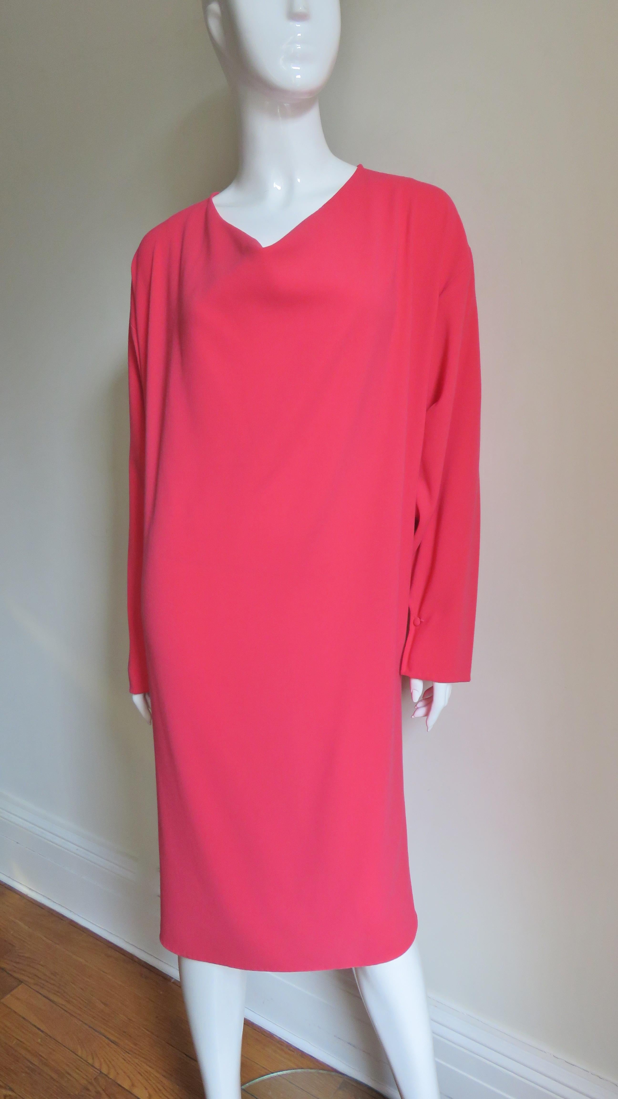 A silk blend sheath dress in a gorgeous shade pink from Halston.  It has a soft V neckline, dolman sleeves with a self covered button at the wrists, and side seam pockets. The dress subtlety  tappers in towards the hem which is hand stitched.  It is