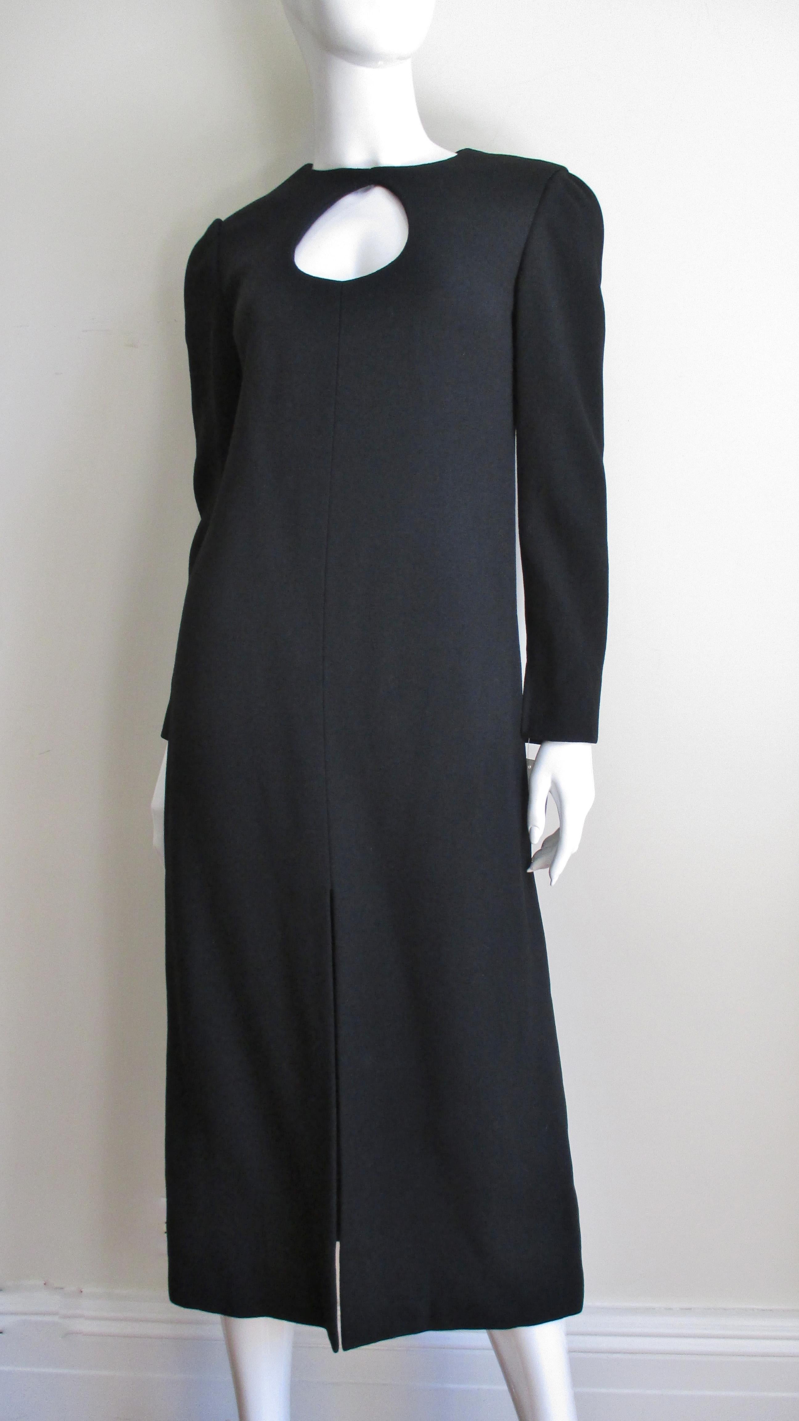 A midi length black wool dress from Pierre Cardin.  It has long sleeves with a tear drop shape cut out at the chest then it flares subtly to the mid calf.  It has a center front slit, a back zipper, and is fully lined in black silk.
Fits size