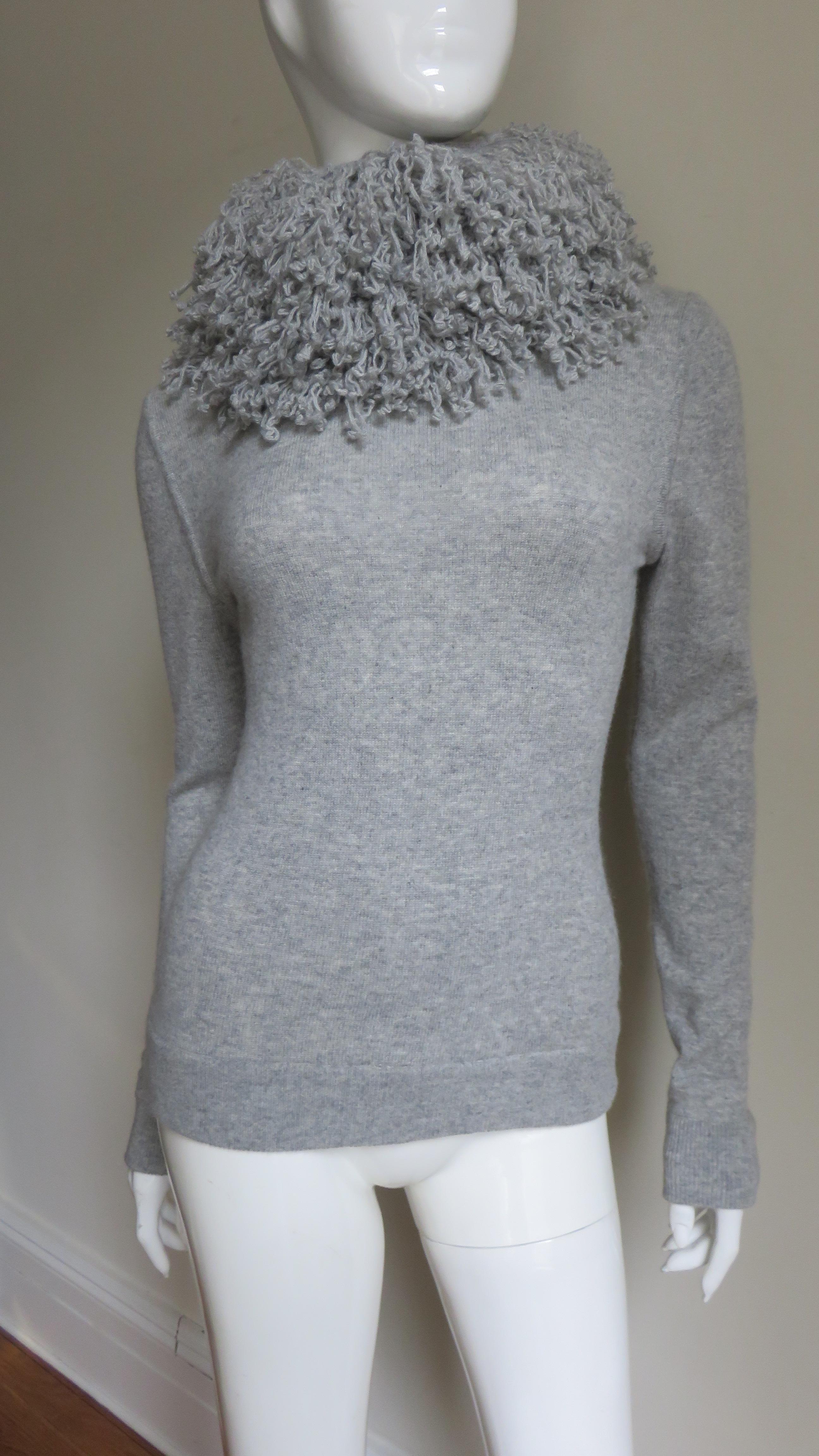A fabulous grey fine cashmere sweater by Laura Biagiotti.  It is semi fitted with long sleeves and a stand up collar comprised of coils of the sweater yarn.   It closes at the back collar with matching mother of pearl buttons and loops and has