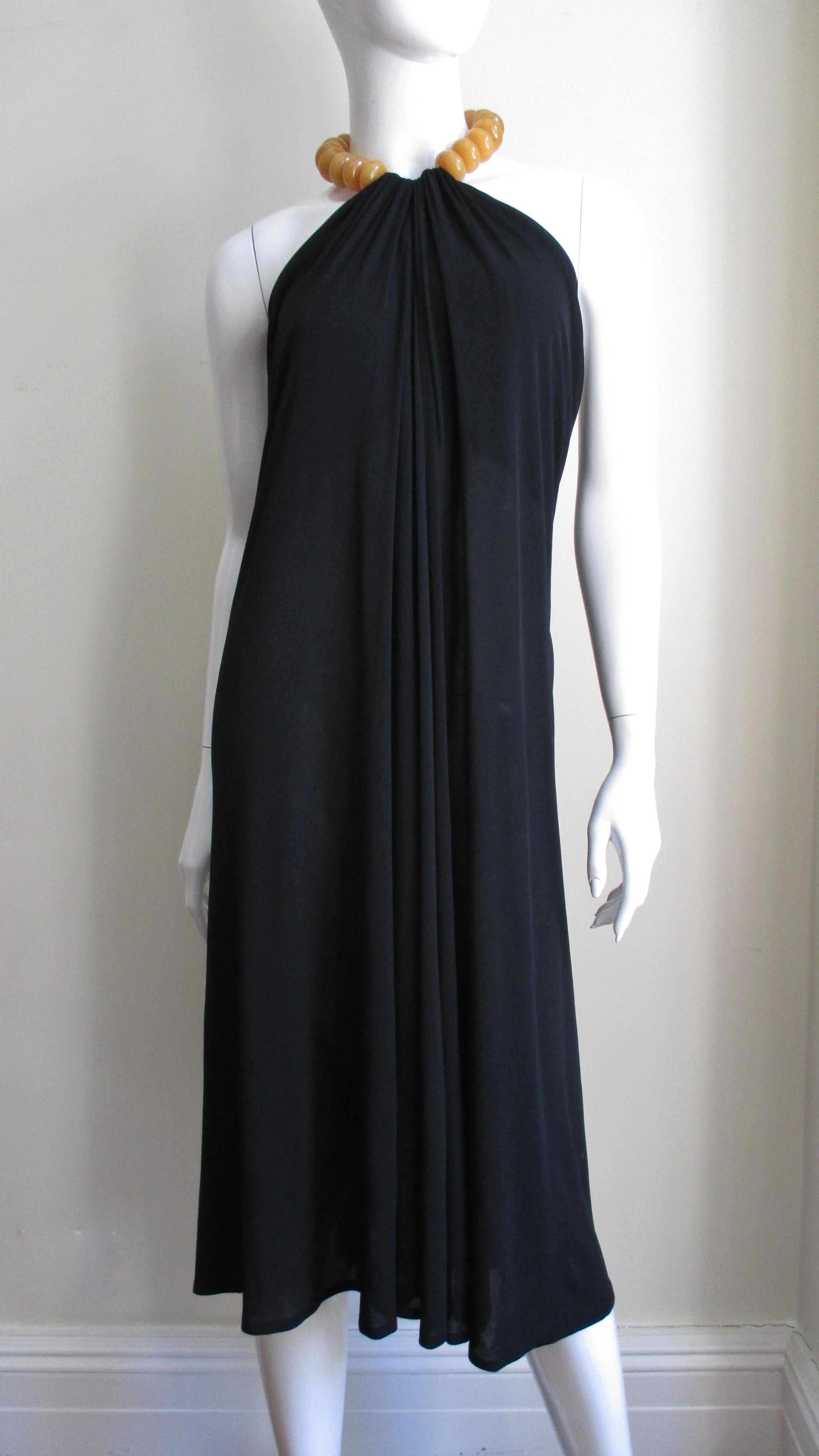 A simple elegant black fine jersey halter dress from Alexander McQueen.  The dress drapes in the front from an adjustable collar of large butterscotch colored beads alternating with small silver metal ball beads with a back toggle closure.  The