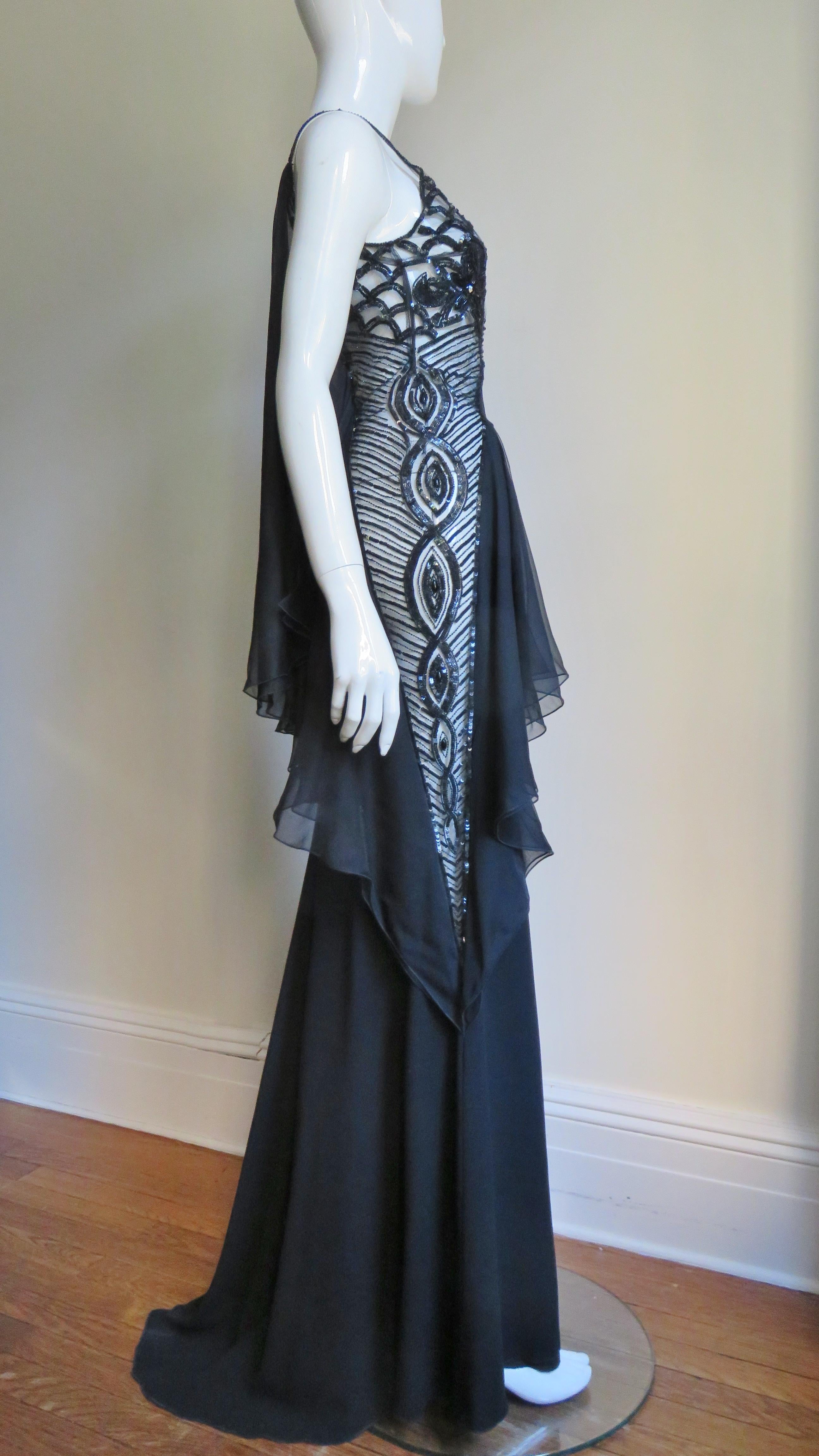 A stunning and rare black silk gown from Valentino.  It has spaghetti straps with a diagonal sheer ruffle framed panel from one shoulder strap across the dress to the opposite thigh covered with lines and circles of sequins on a net background