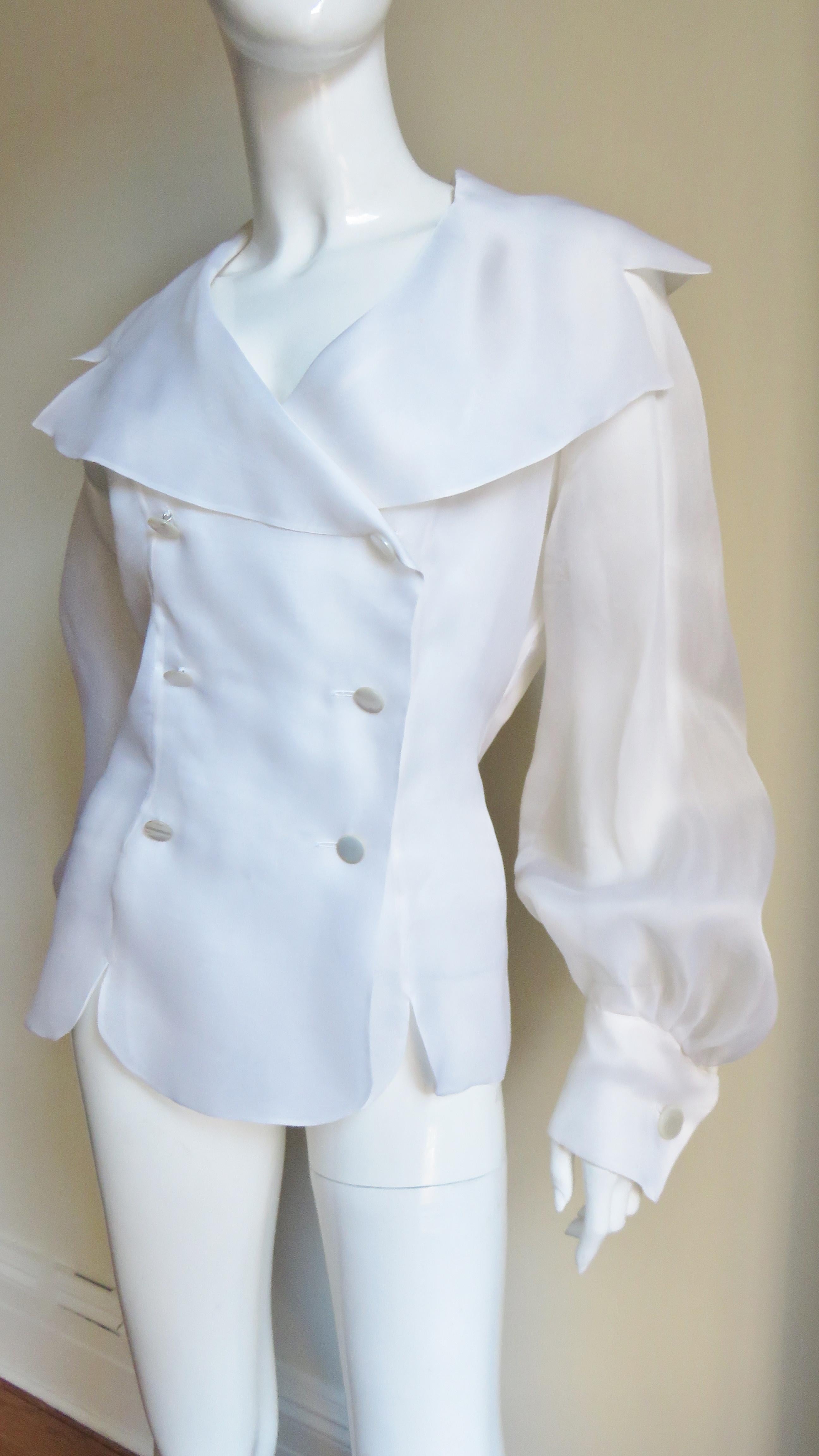 A gorgeous white silk organza blouse, shirt, top by Emmanuelle Khanh.  It is double breasted with large mother of pearl buttons and a large notched portrait collar.  The long, full raglan sleeves have french cuffs with matching mother of pearl cuff