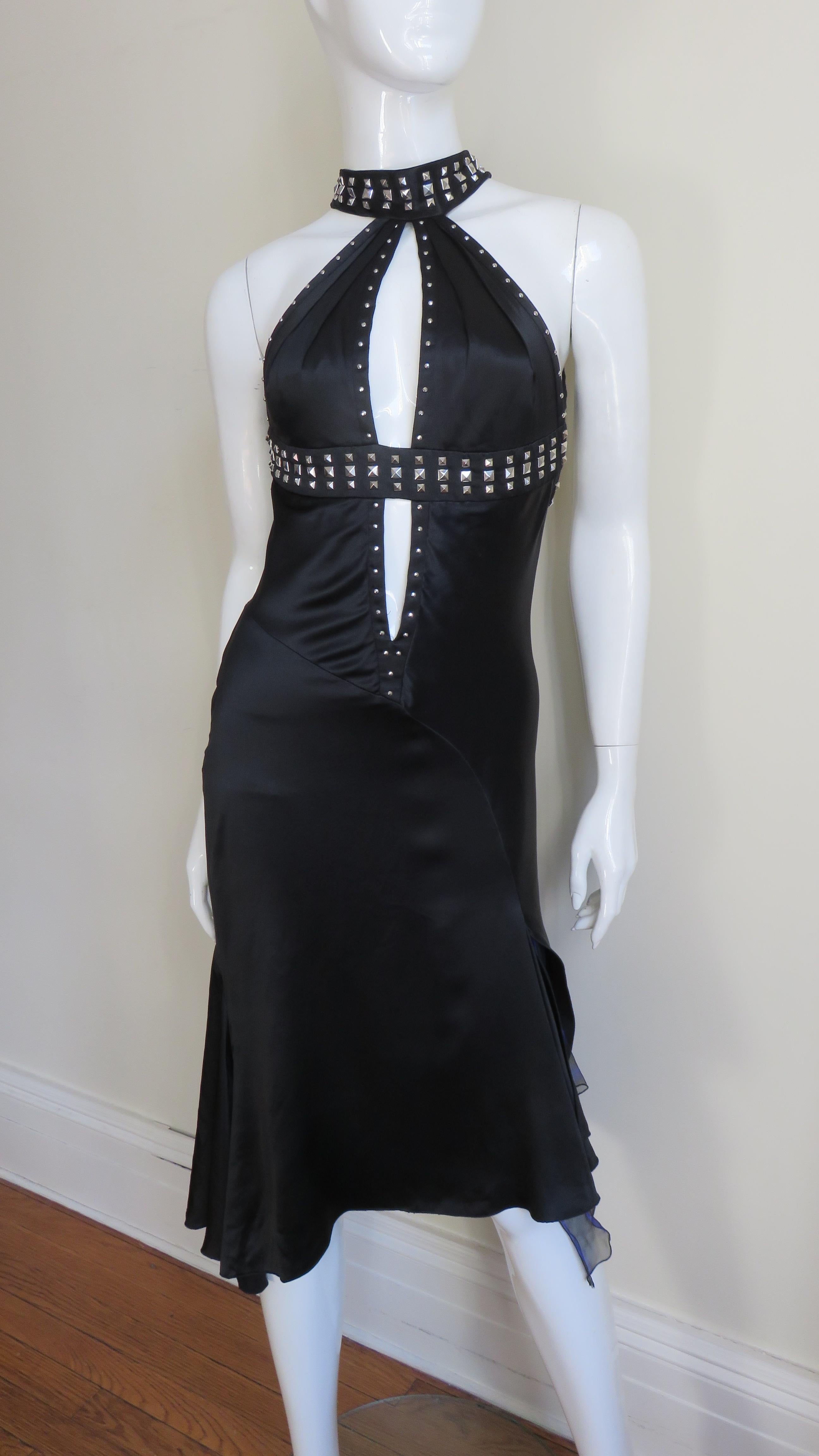 A stunning black silk dress from the Versace S/S 2004 Collection. It has square silver metal studs along the straps which wrap around the neck, crossing the upper back then wrapping under the bust where it divides a center front keyhole outlined in