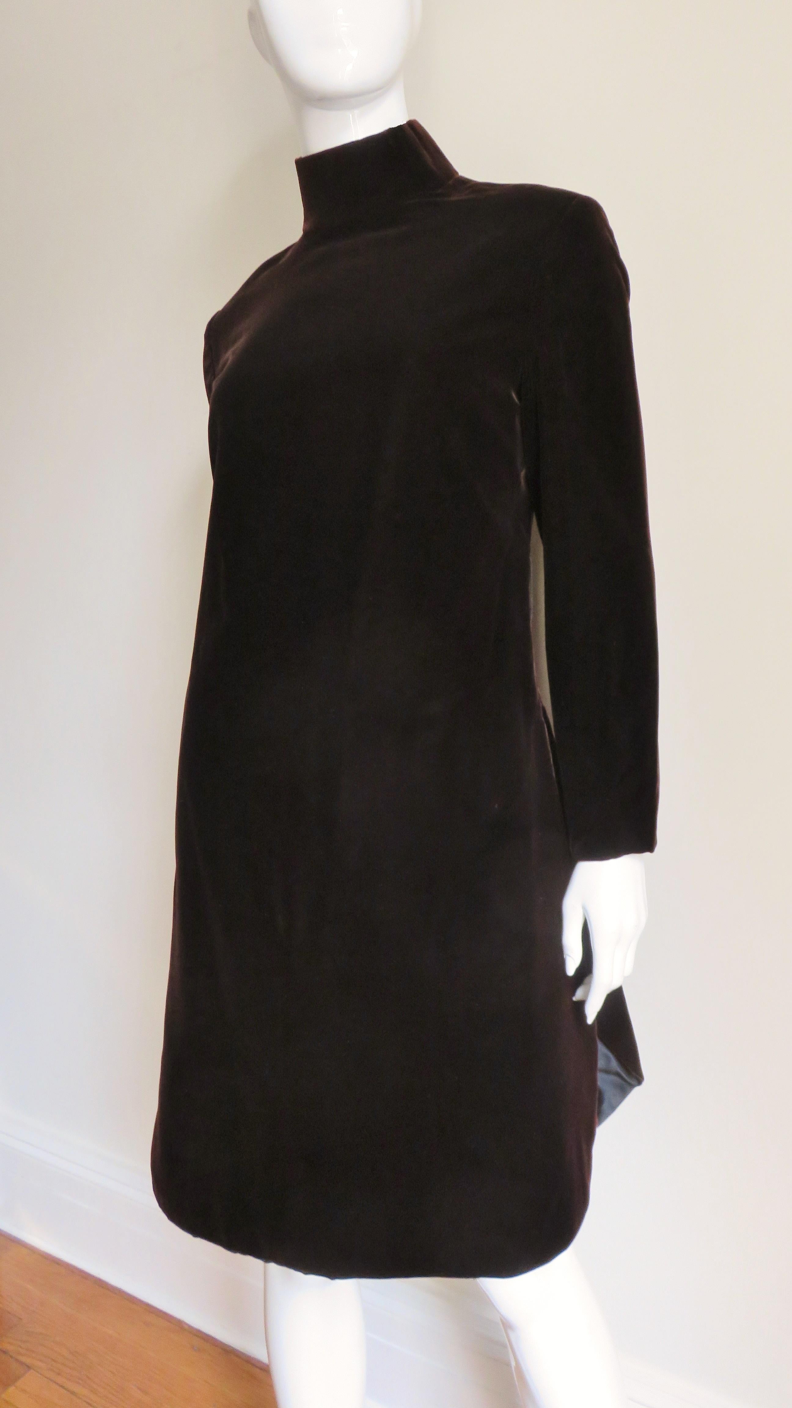 A rich brown silk velvet dress from Pierre Cardin.  It has a stand up collar, long sleeves and a shirt tail hemline which reveals a straight black silk under skirt at the sides.  It comes with a wired gold lurex tie belt, is fully lined in black