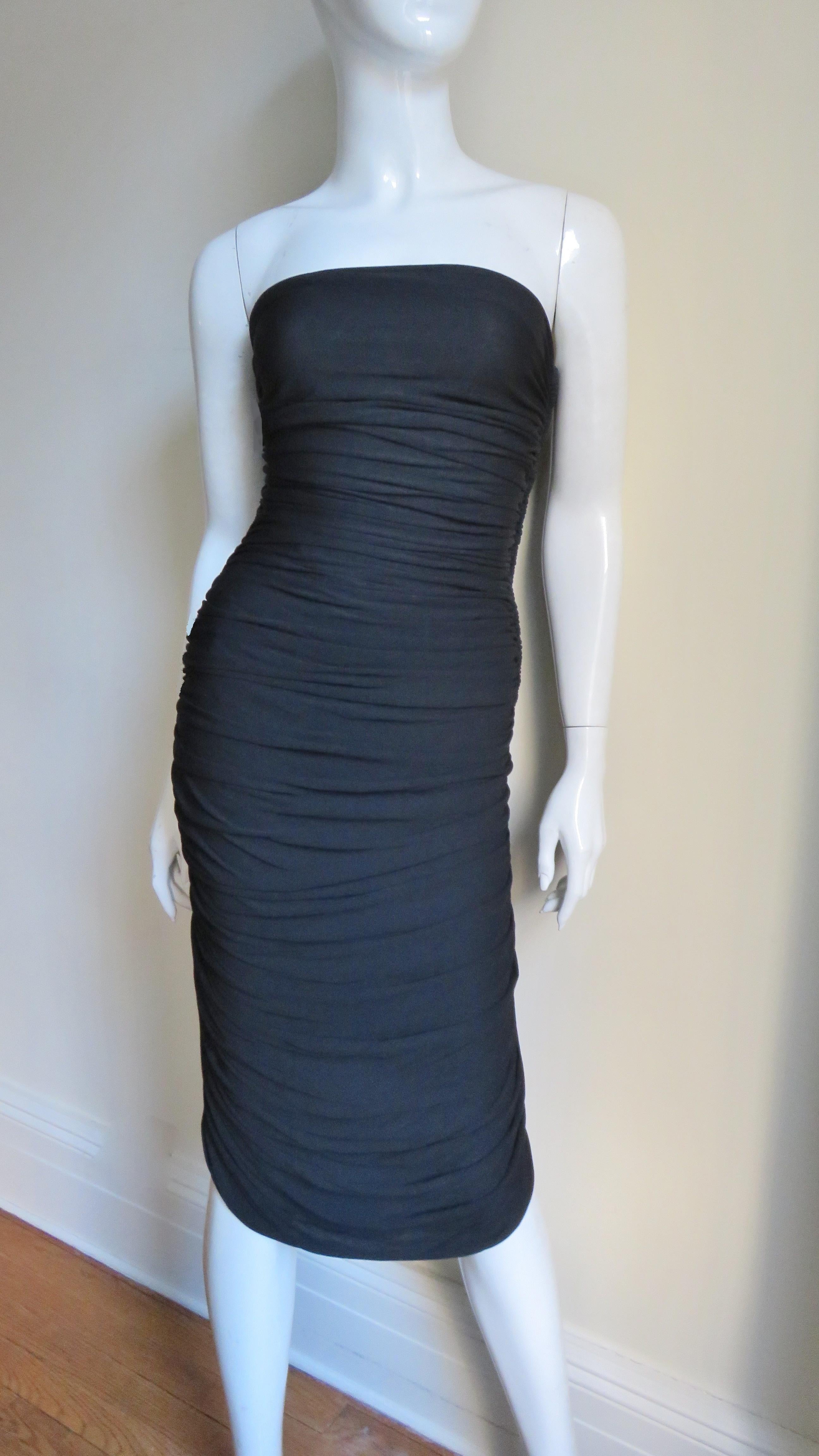 A pretty black slinky dress with stretch from Vicky Tiel.  It is strapless and horizontally ruched from top to bottom front and back. The bodice has side boning, a side zipper and the dress is lined. 
Fits sizes S, M. Marked French size 40.

Bust 
