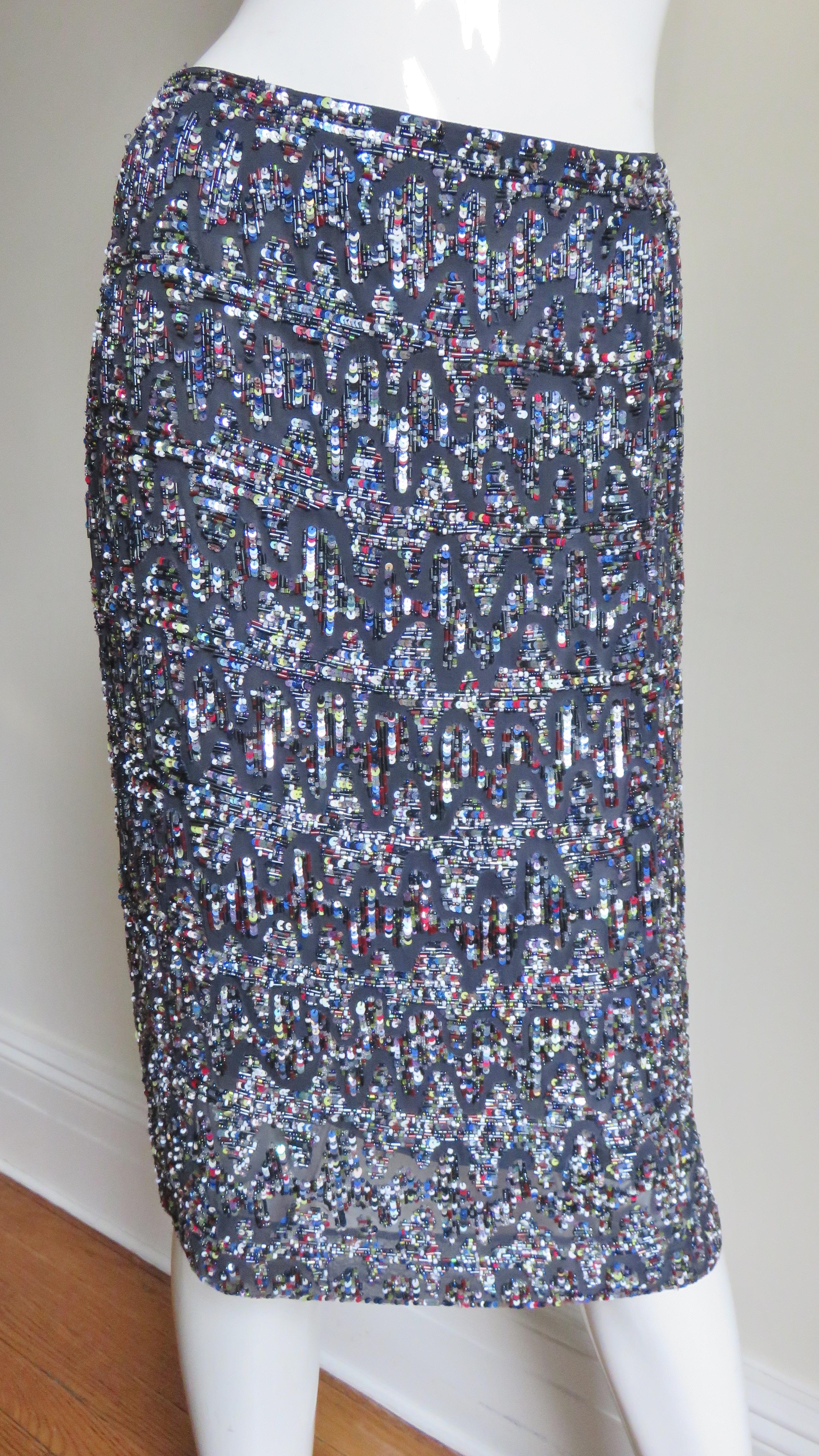 A gorgeous charcoal silk pencil skirt from Rena Lange covered in an elaborate pattern of white, silver, grey and red sequins, seed beads and glass tubular beads.  It is lined in the same charcoal silk and has a matching side zipper.
Fits sizes