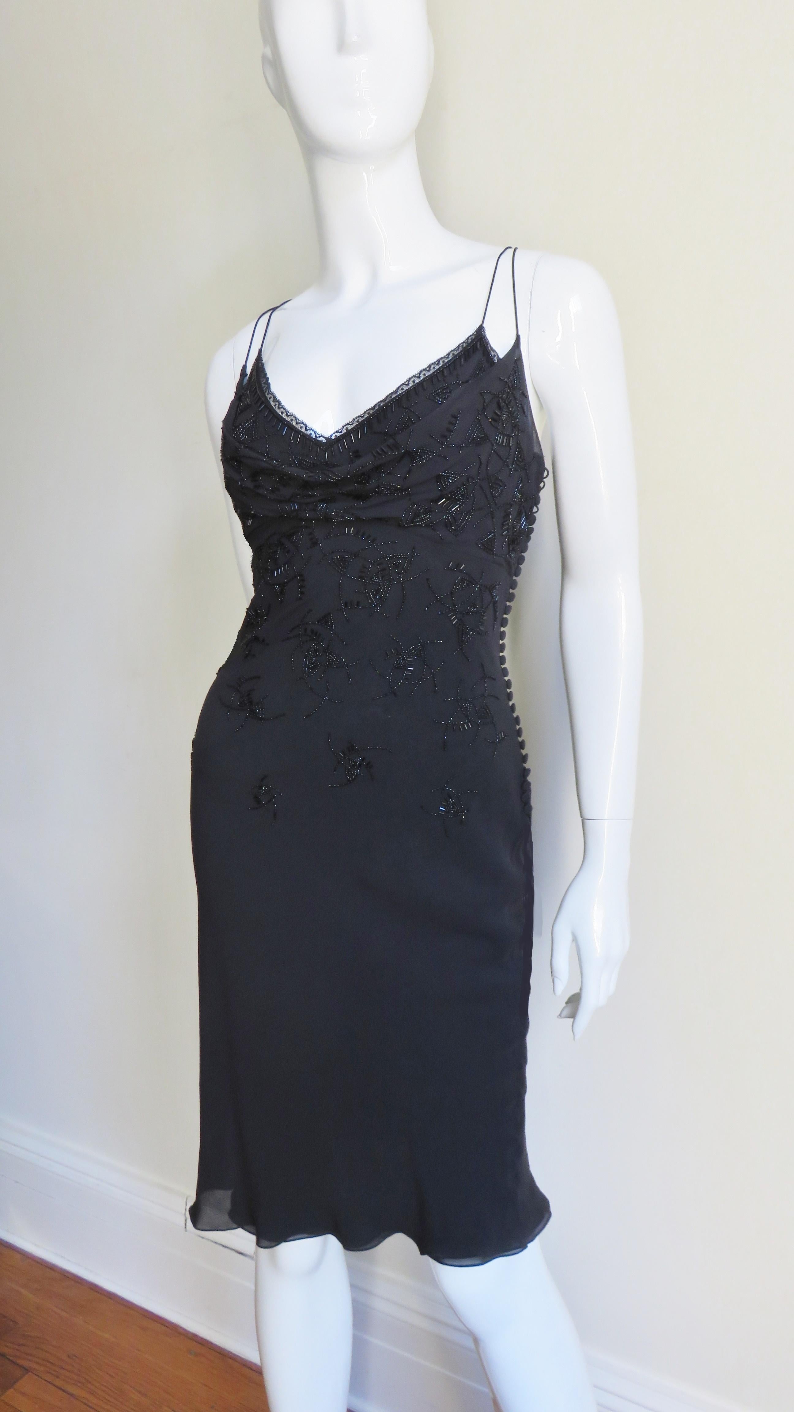 A gorgeous black silk slip dress from Christian Dior. The dress skims the body with a small flare towards the hem and has double spaghetti straps plus a lace trimmed neckline with an abstract pattern of black glass tubular and round seed beads that