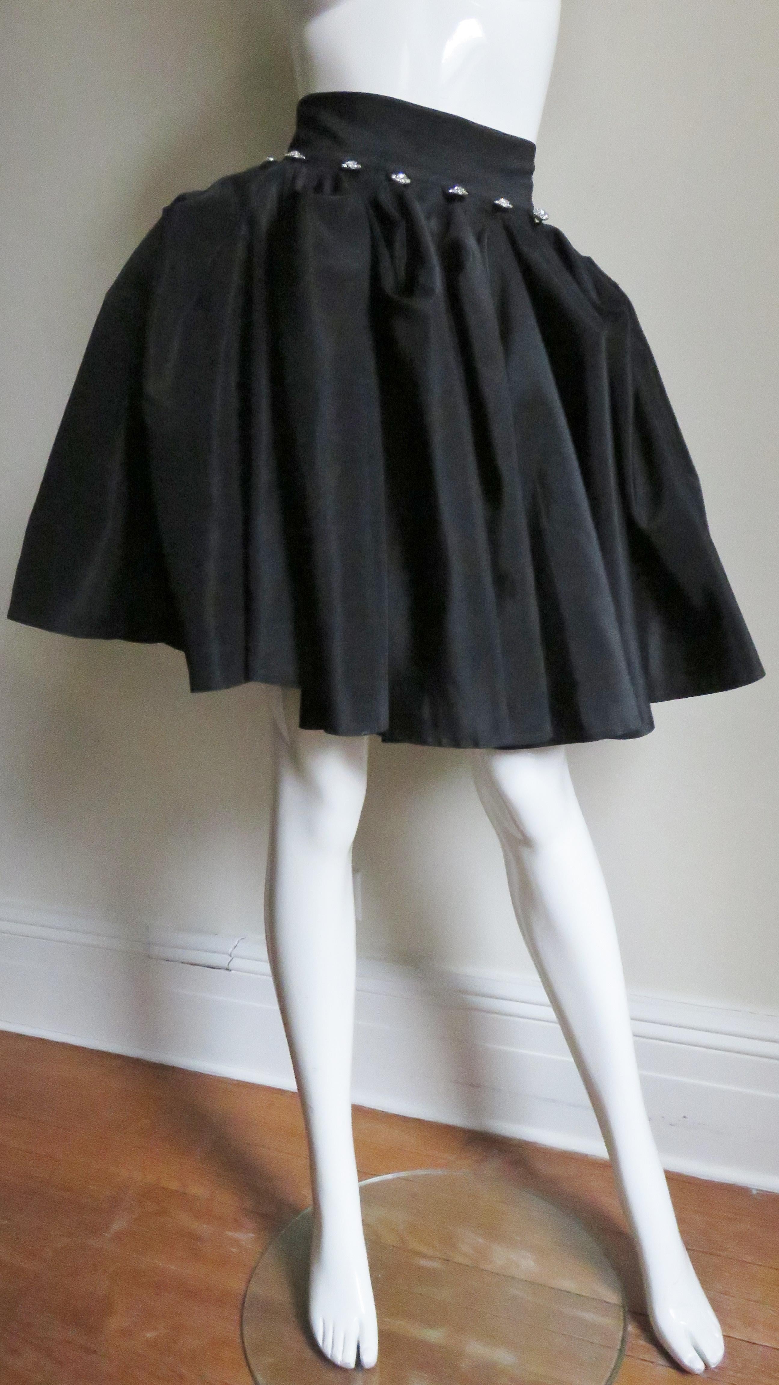 An ingenious design in a long taffeta skirt that converts into a knee length skirt or half up and half down. The full circle skirt has 15 faceted rhinestone buttons sewn at the half way point around it's circumference which can be buttoned onto