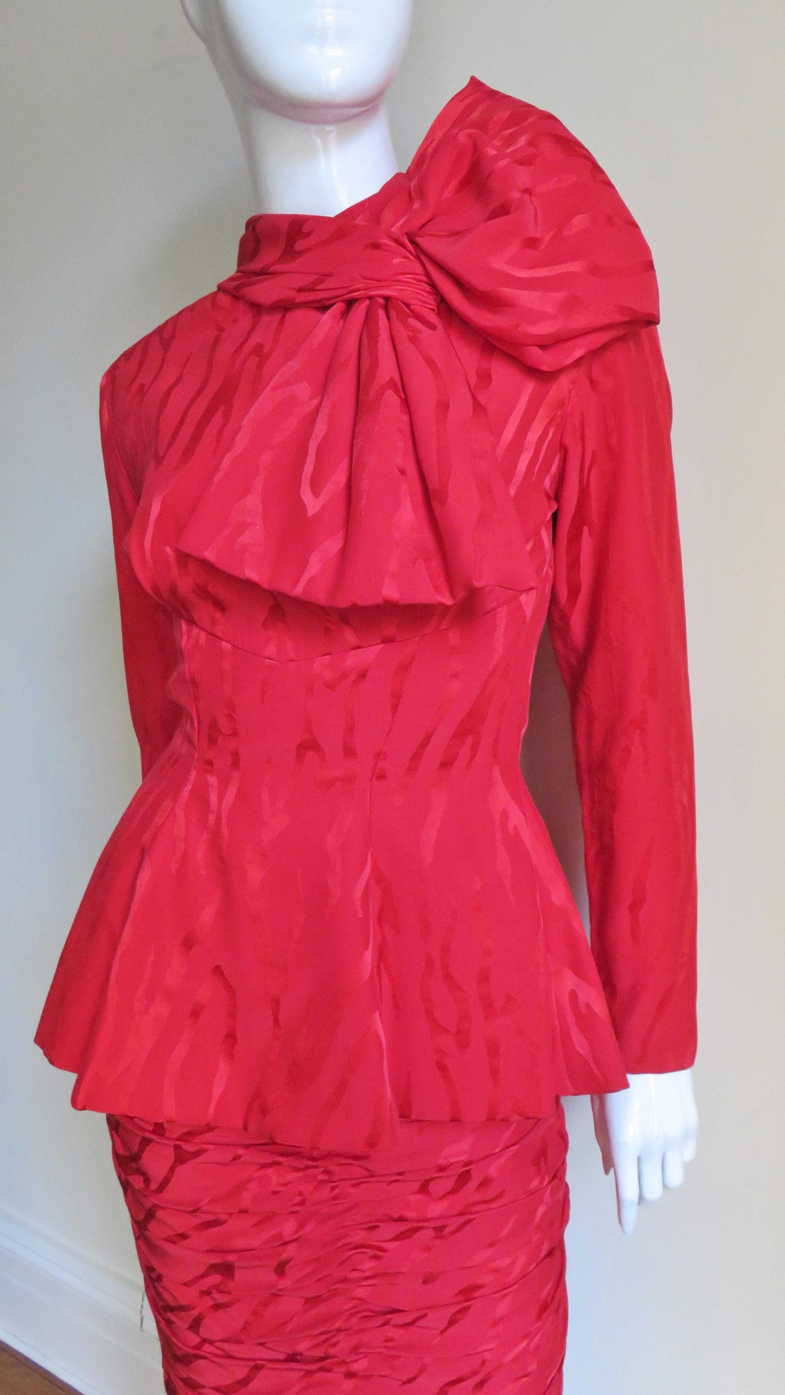 A beautiful red silk damask 2 piece skirt and top set from Vicky Tiel's couture collection. The long sleeve top is fitted at the waist with an inset at the front and back to above the waist then flaring towards the hip length hem. There is a large