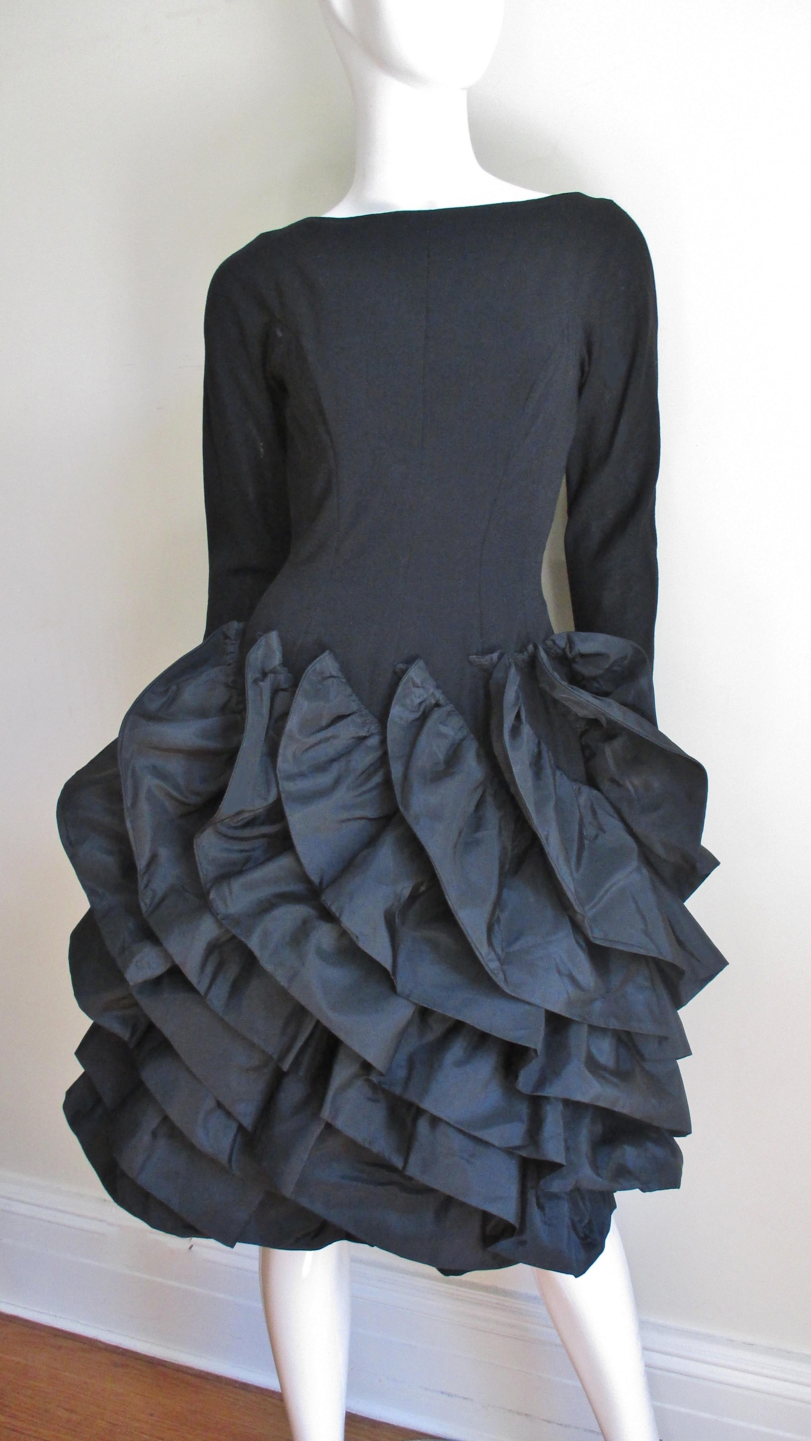 Une fabuleuse robe légère en laine et soie noire de Betty Carol. Elle présente des coutures princesse pour une excellente coupe, un dos coupé en V et une incroyable jupe entièrement ornée de rangées de taffetas en spirale. Les volants sont appliqués