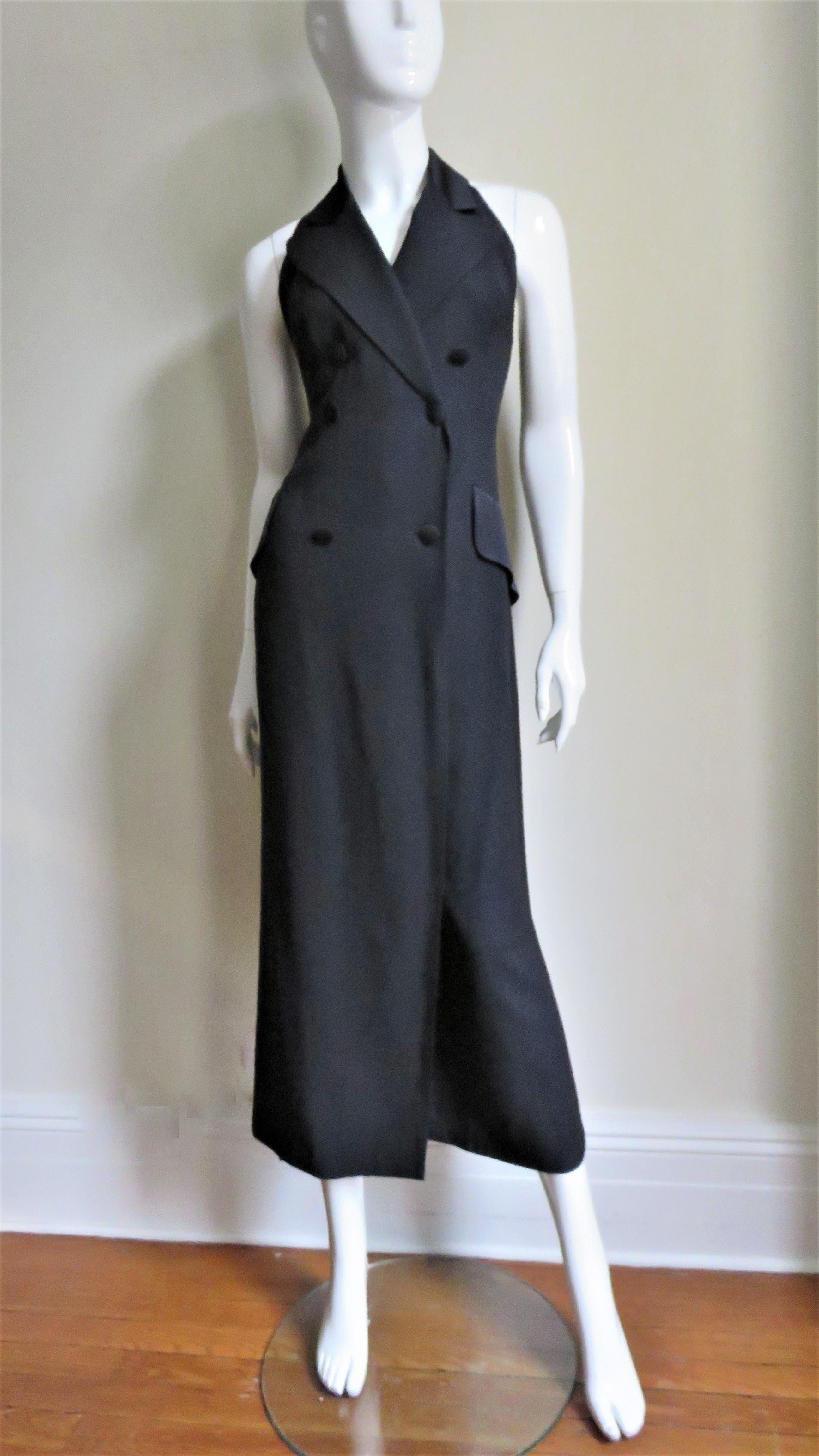 A fabulous black halter jumpsuit from Moschino.  It is double breasted with 6 buttons matching the satin peak lapels and hip pocket flaps. Semi fitted through the waist the lower portion becomes full leg pants with a front flap over them, appear as