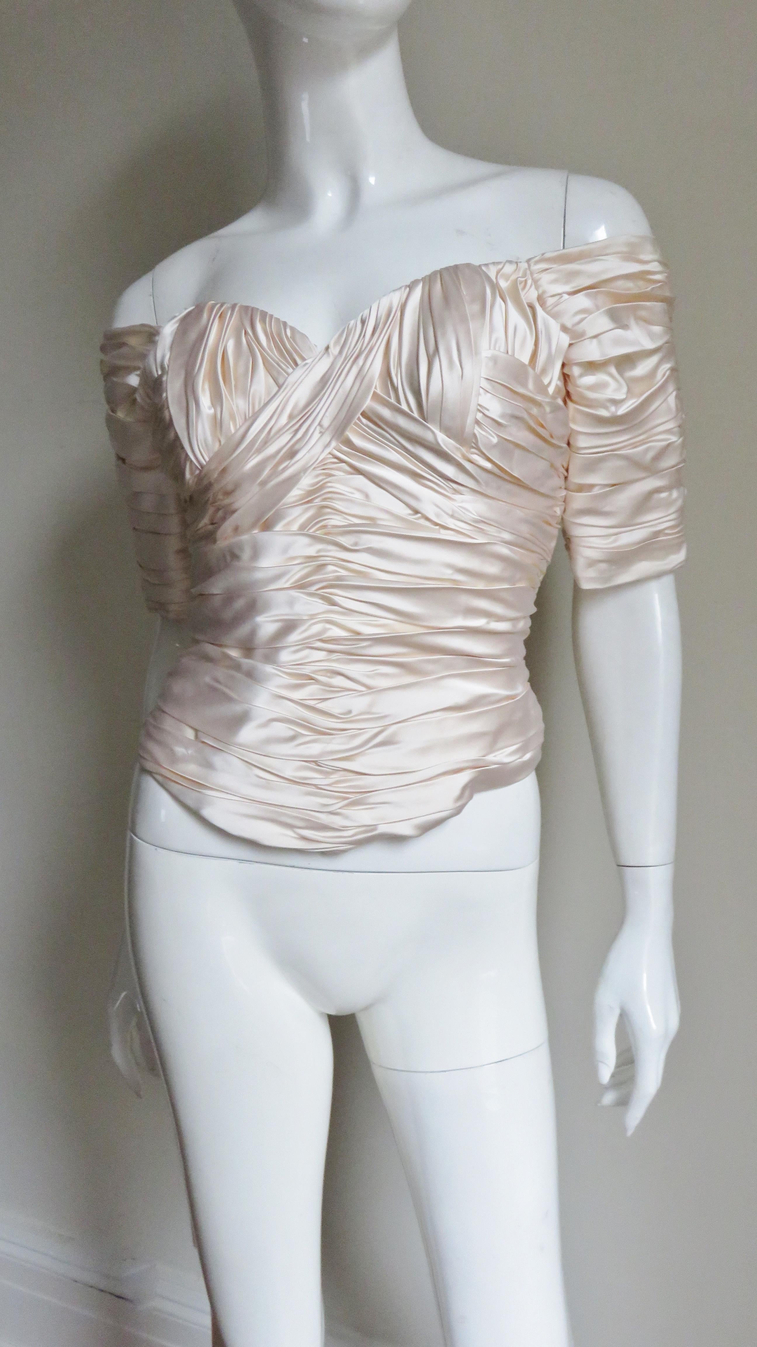 A beautiful off white silk corset top from Vicky Tiel.  It is worn off the shoulders with elbow length sleeves, a sweetheart cut neckline and ruching throughout in angles.  The front and back hem dip a bit longer in the center.  It has vertical