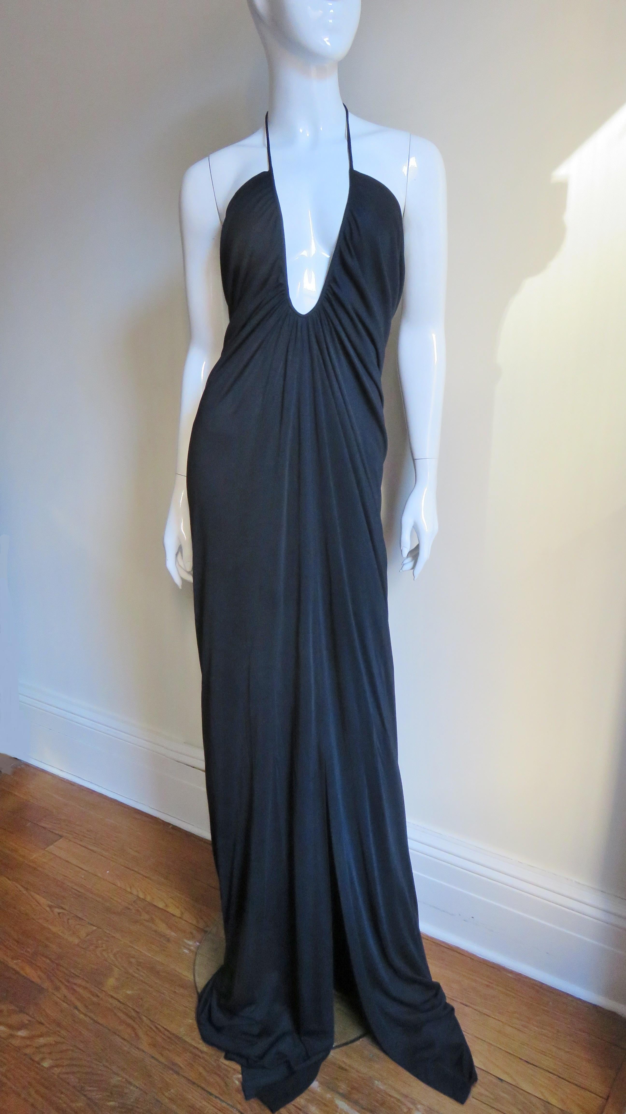 A gorgeous black jersey dress from Gucci.  It has a deep plunging rounded V front adjustable tie halter neckline, the back drapes to just below the waist.   There are metal Gucci engraved aglets on the ends of the ties at the neck and a slit at the