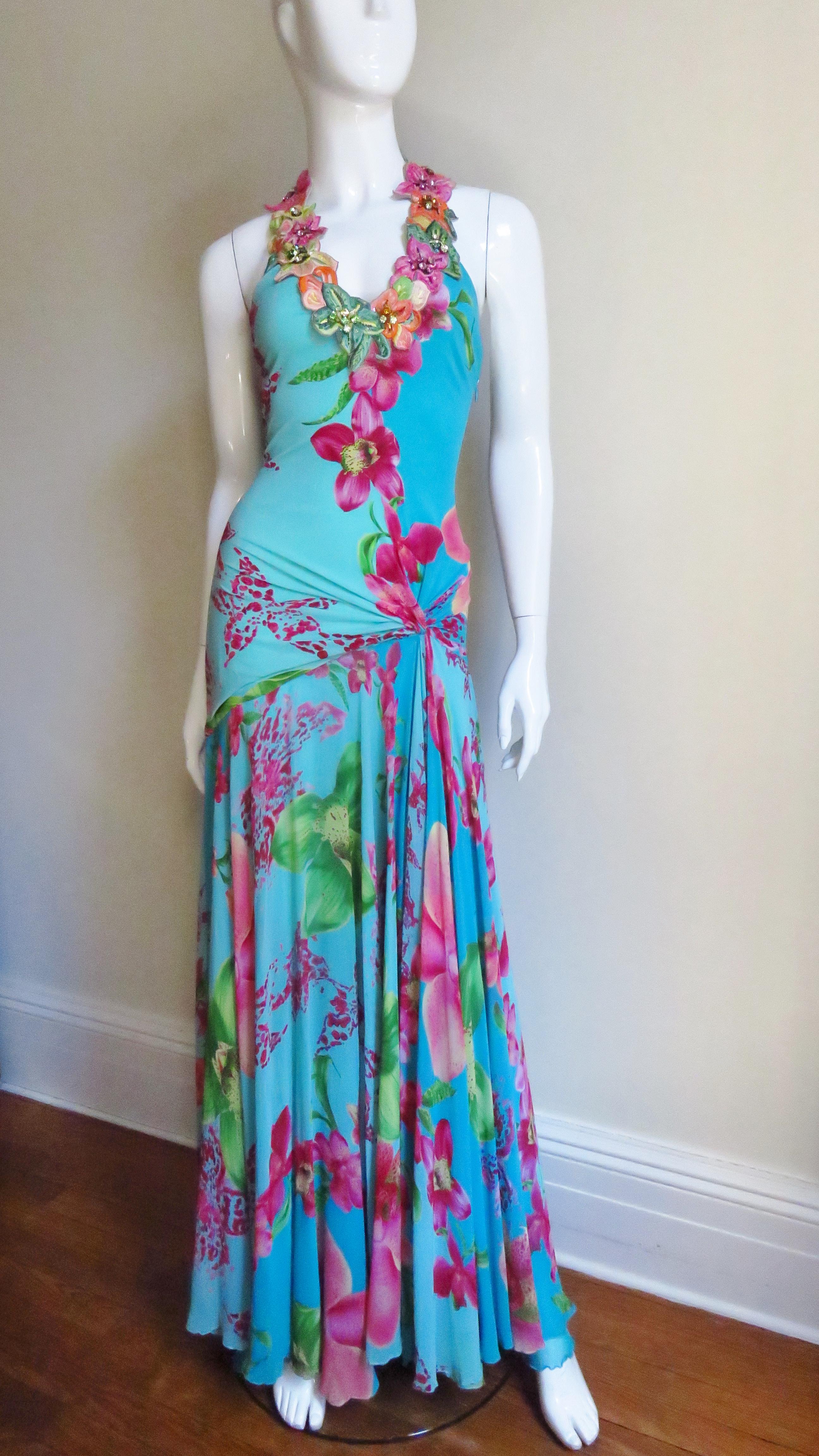 A gorgeous turquoise blue silk jersey and silk chiffon dress from Versace in a pink and green flower pattern.  It has a plunging neckline framed with intricately embroidered flowers highlighted in their centers with several colorful rhinestones and
