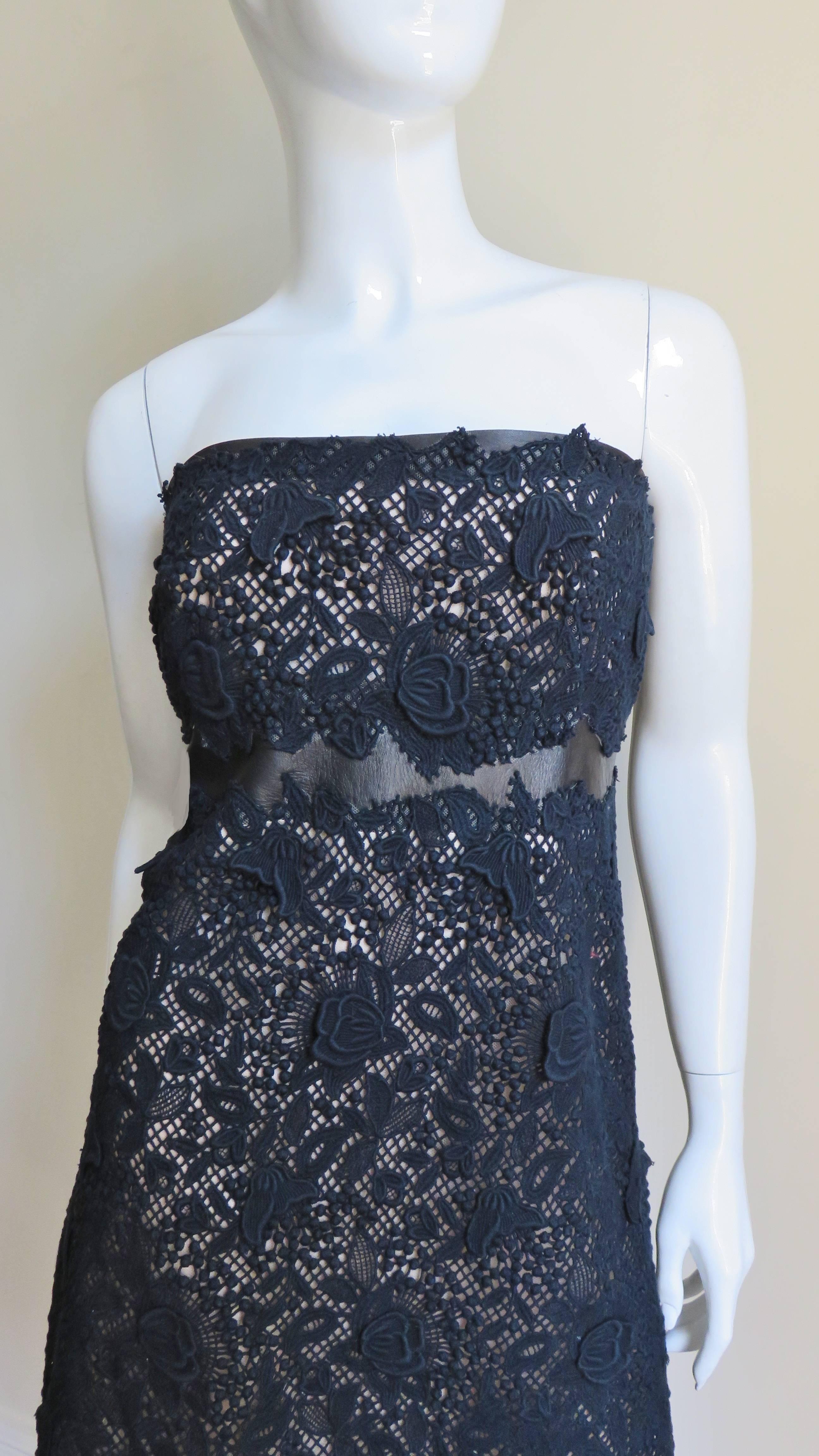 A fabulous strapless black lace dress from Valentino. The body of the dress is comprised of rich elaborate black floral lace with a black leather band above and below the bust around the circumference of the dress. The bodice has an inner boned