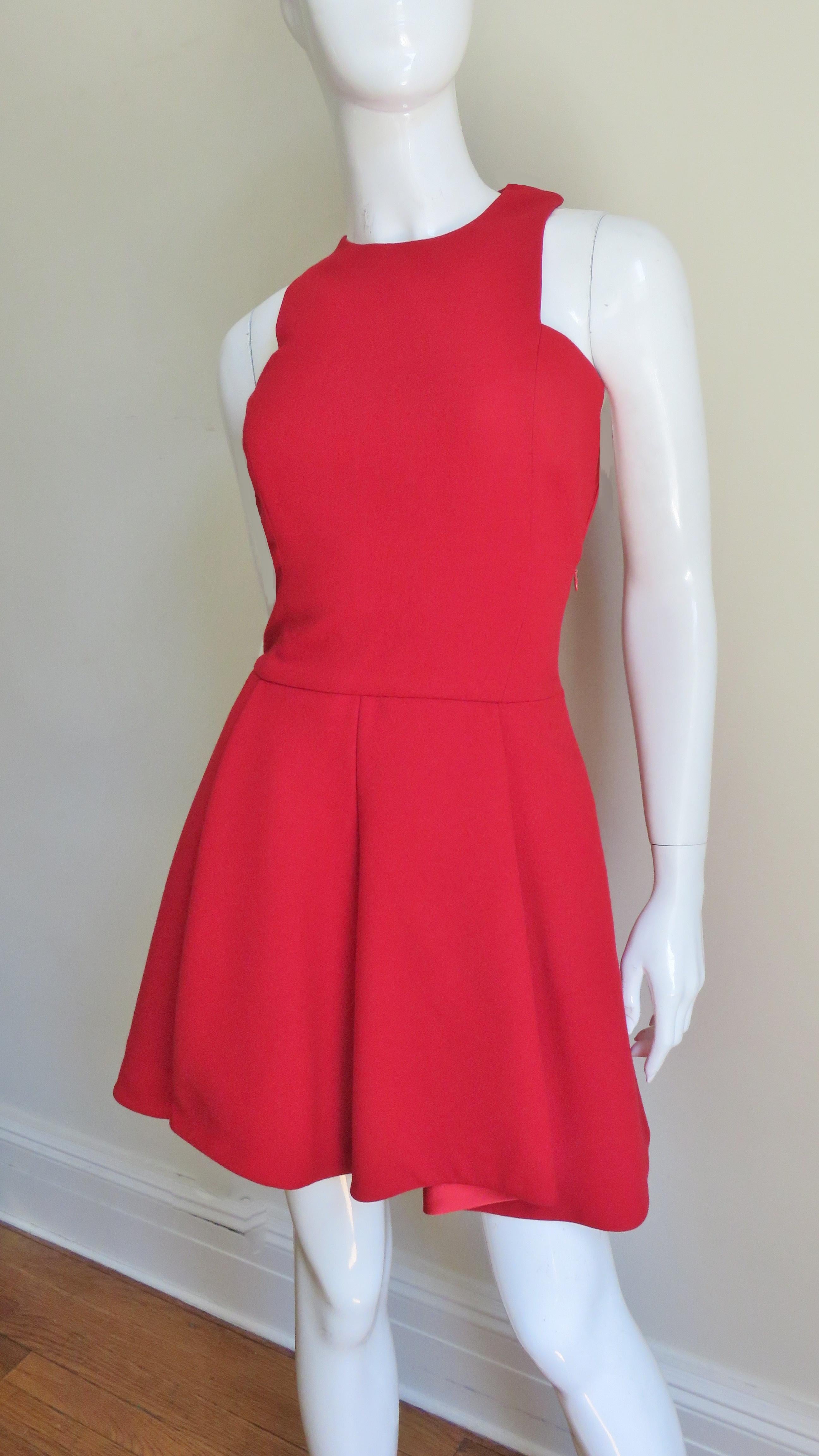 Un impresionante vestido rojo de lana de Gianni Versace. Tiene unas líneas estupendas con sisas de corte cuadrado, un corpiño ajustado y una fabulosa falda acampanada con la espalda unos centímetros más larga y con más volumen que la parte