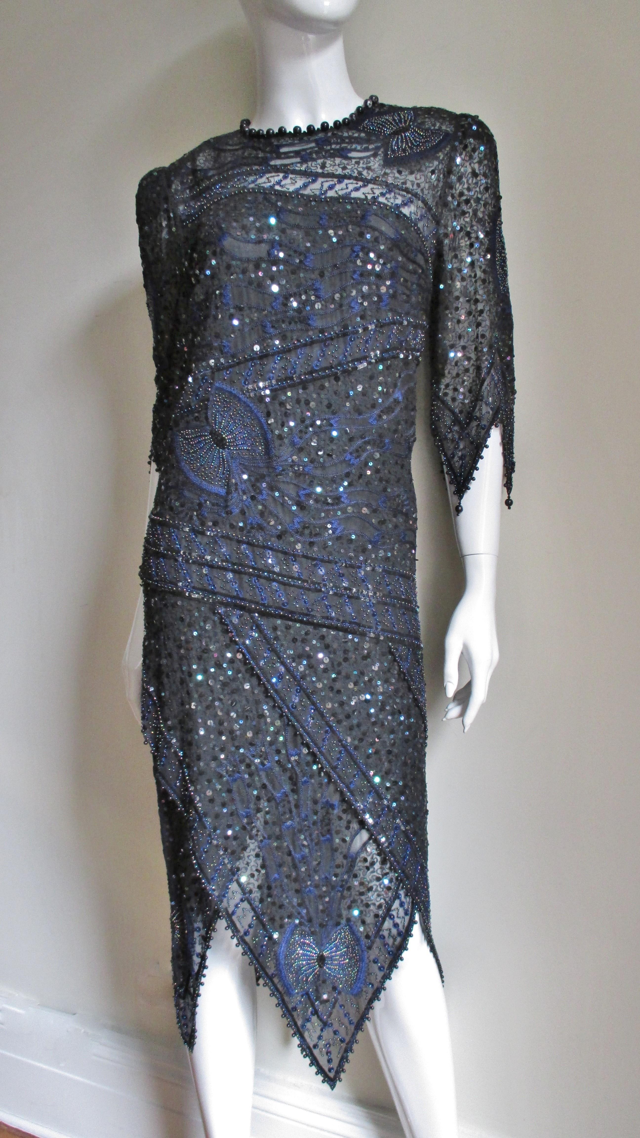 A gorgeous bead, sequin and blue embroidery dress from Zandra Rhodes made of semi sheer black silk. There are intricately beaded butterflies sprinkled throughout and bands that cross the dress on an angles front and back.  It has elbow length