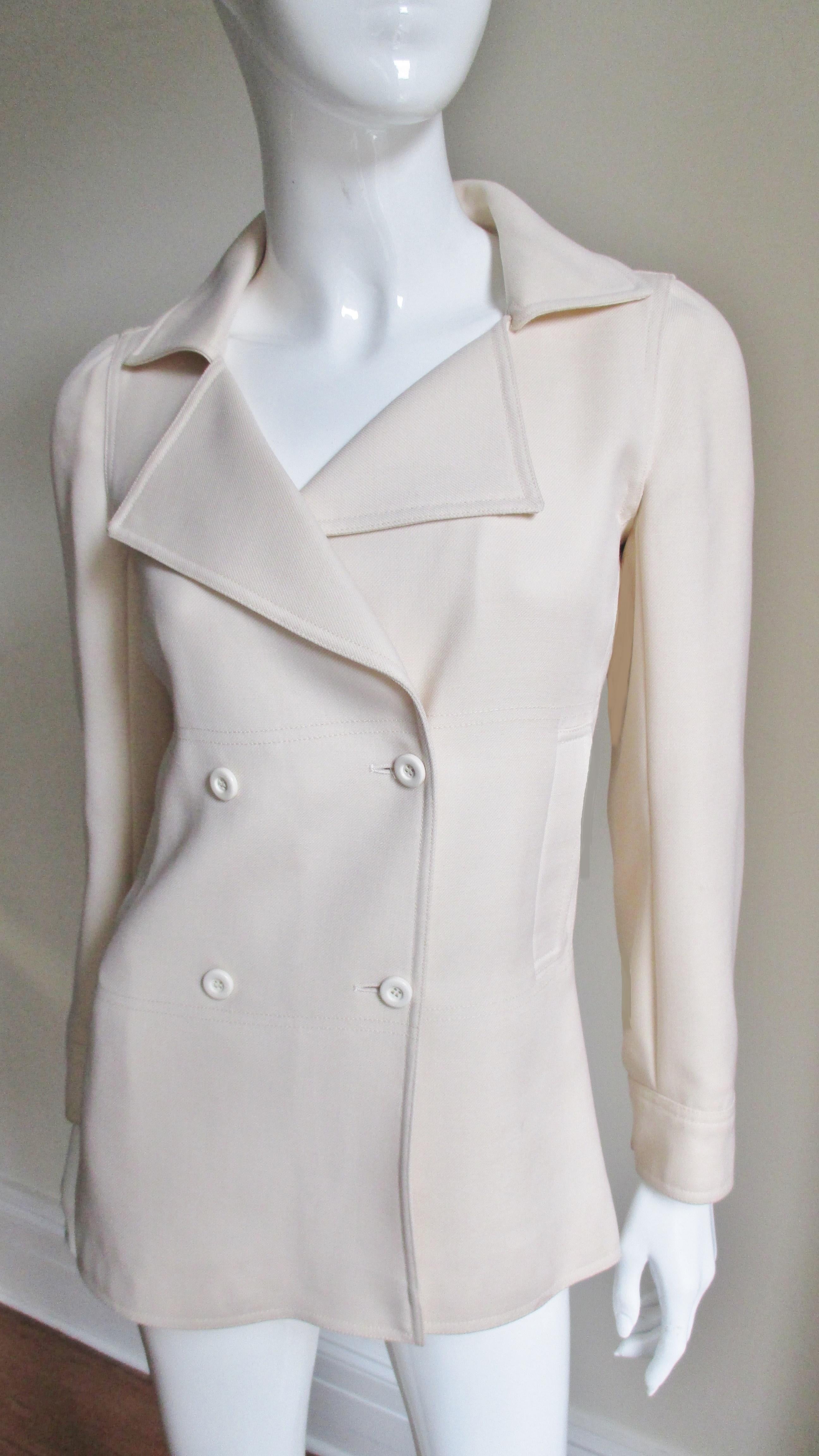 A fabulous jacket in off white wool twill from Courreges.  It is double breasted with has full notched lapels, matching off white buttons and 2 side waist front pockets.  The long sleeves have cuffs with a matching buttons.  There is a back a panel