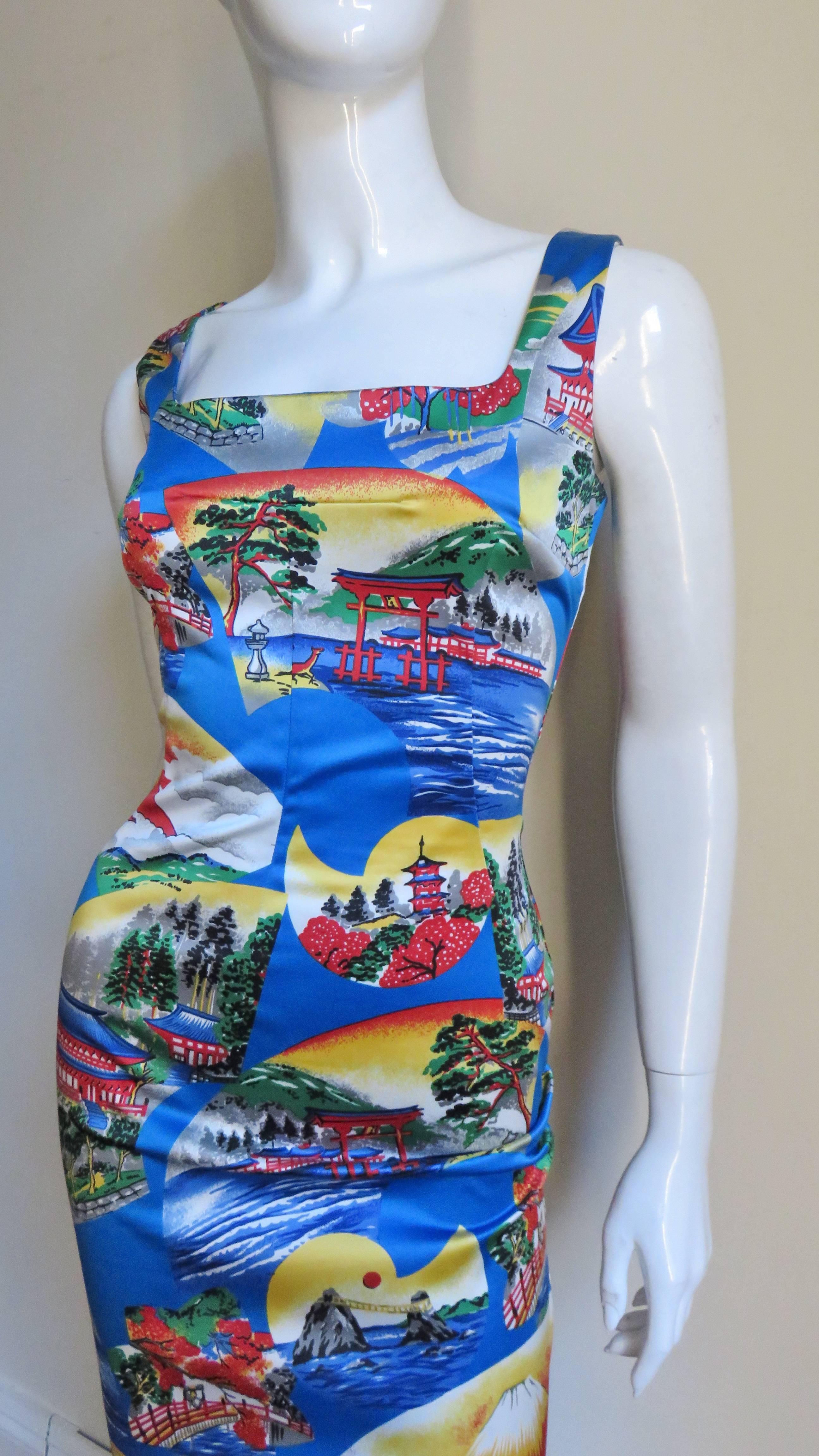 A bodycon dress covered in scenes of pagodas, Mount Fuji, cherry blossom trees and idyllic water scenes from Dolce and Gabbana in bright blue, red, white and green.  It is fitted with a front square cut neck and back scoop neck.  Front princess