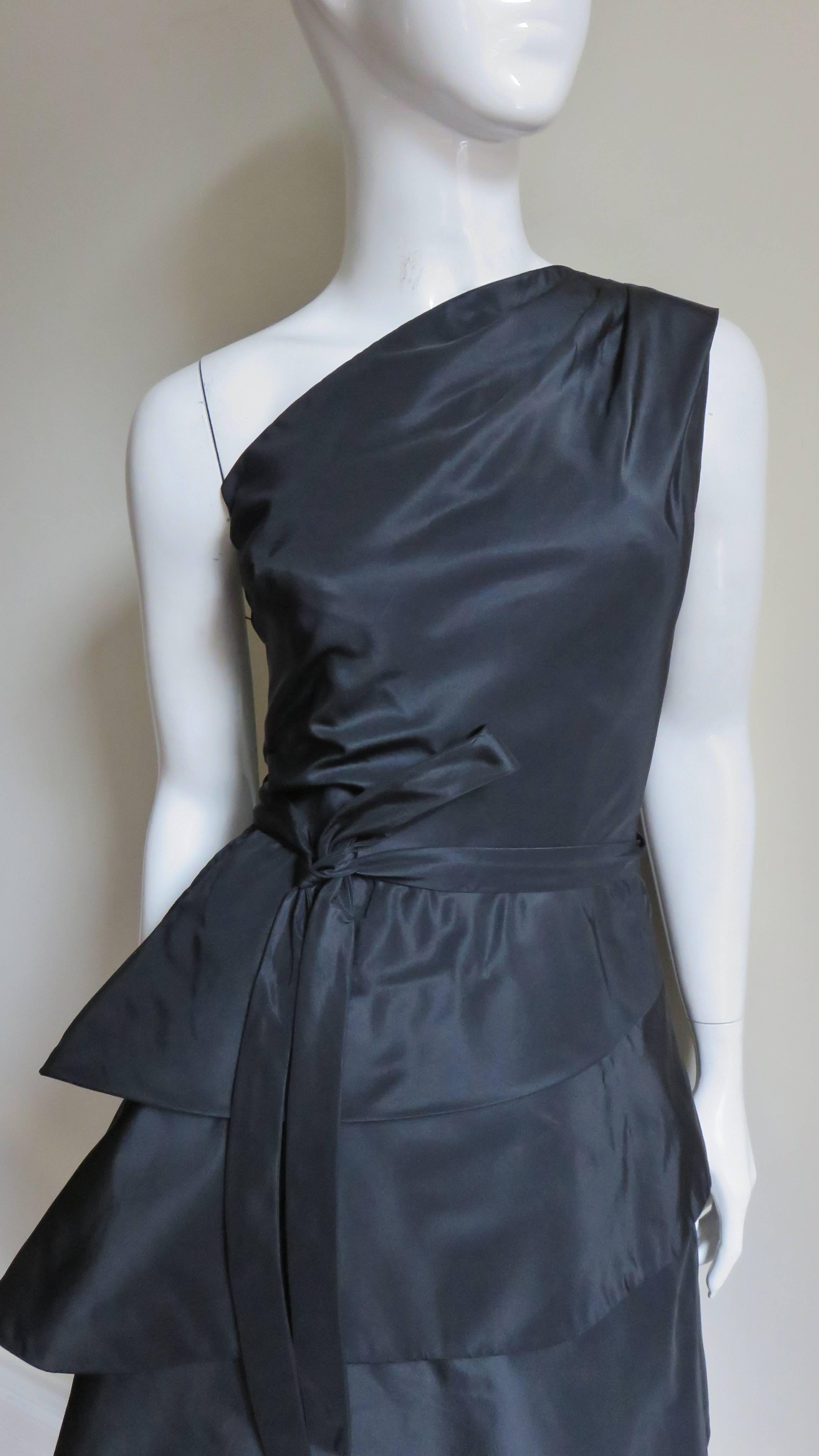 A stunning sculptural black silk dress from Werle, Beverly Hills.  It has a one shoulder fitted bodice with an inner boned corset. The skirt consists of 1 tier wrapping horizontally around the straight skirt 3 times.  It closes with a fine side