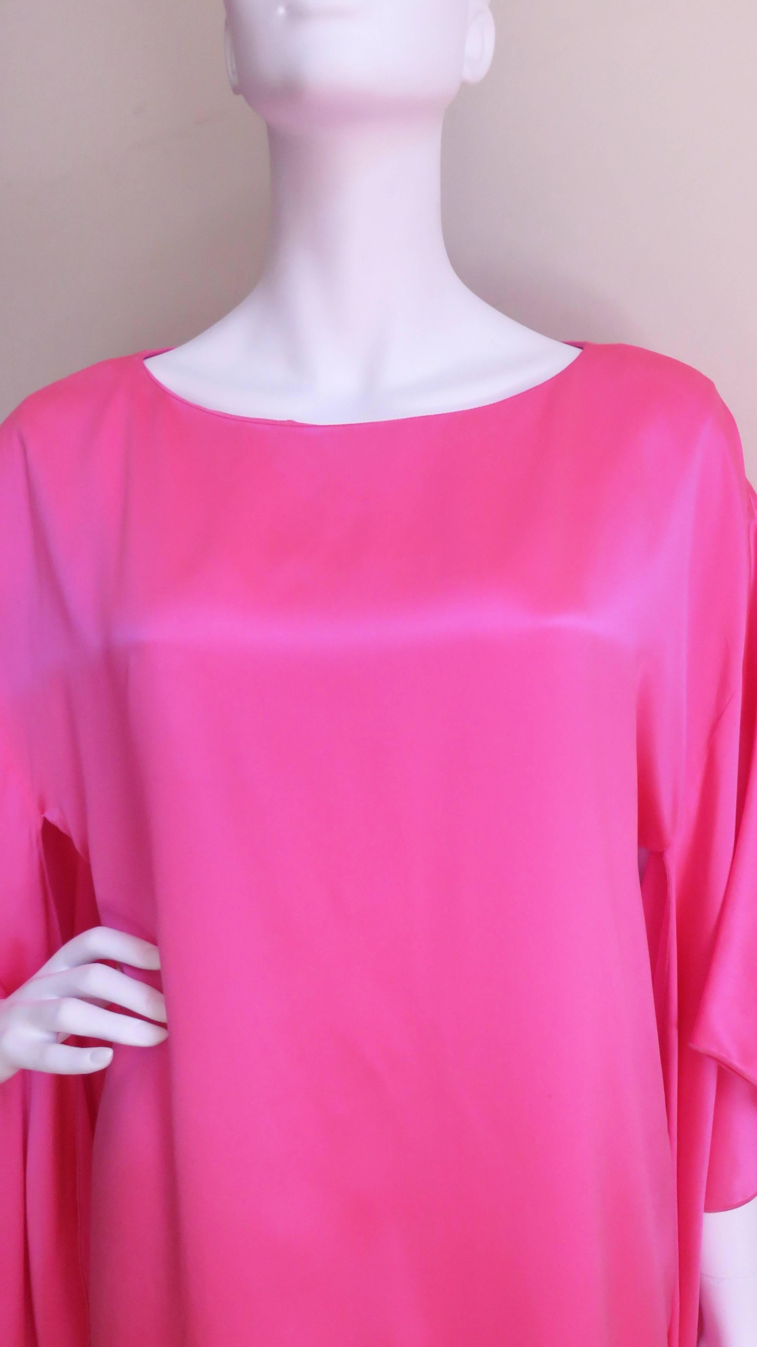 A beautiful vibrant pink silk mini dress from Holly Harp.  It has a crew neckline with a back keyhole and a self covered button above it.  The dress is cut straight from the shoulders with amazing angel wing sleeves draping the length of the dress.