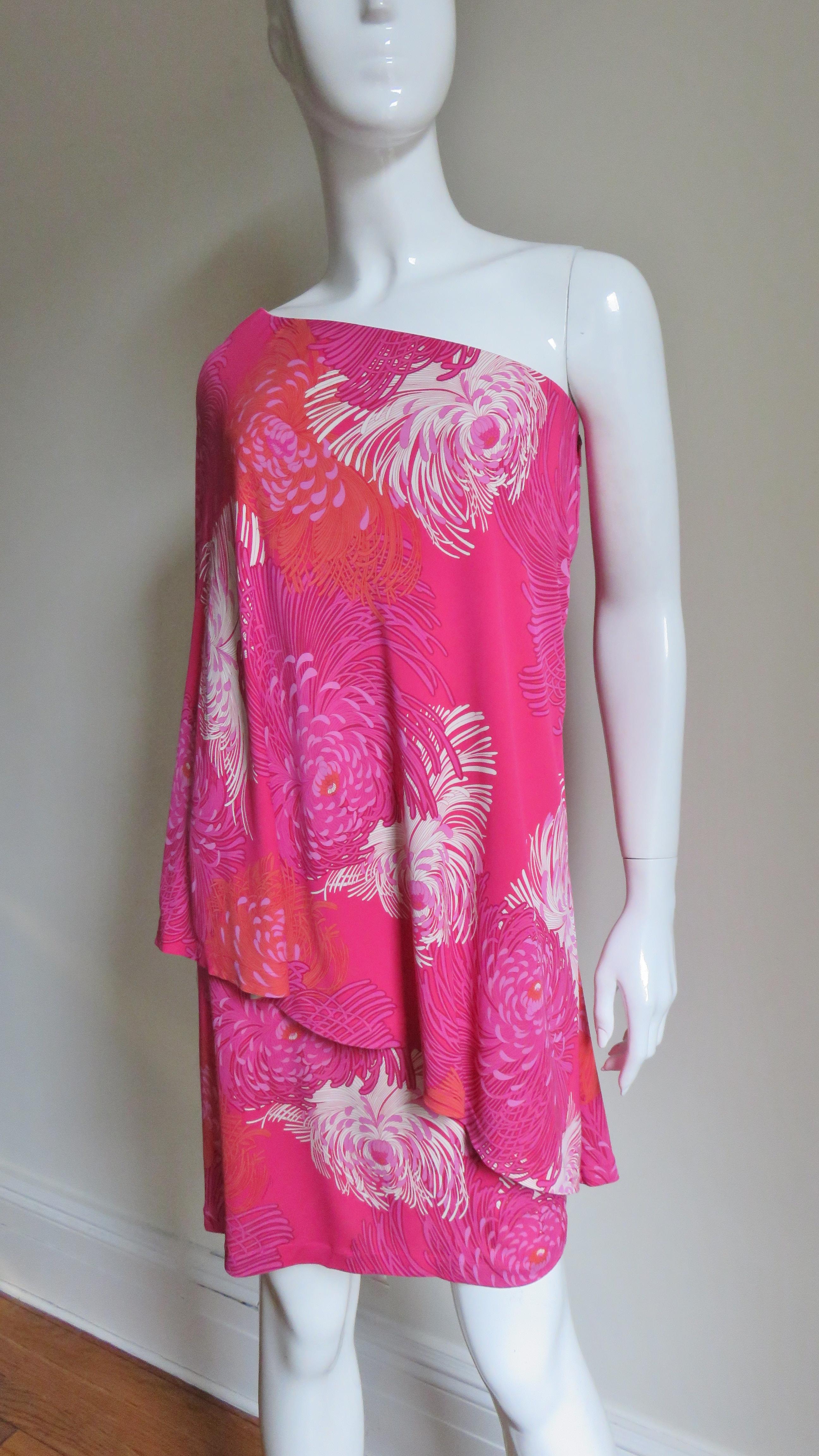 A beautiful chrysanthemum print silk jersey dress in shades of pink and white by Frida Giannini for Gucci.  It has one full sleeve with draping diagonally across the front of the dress.  It is lined in nude silk and has a matching side zipper with a