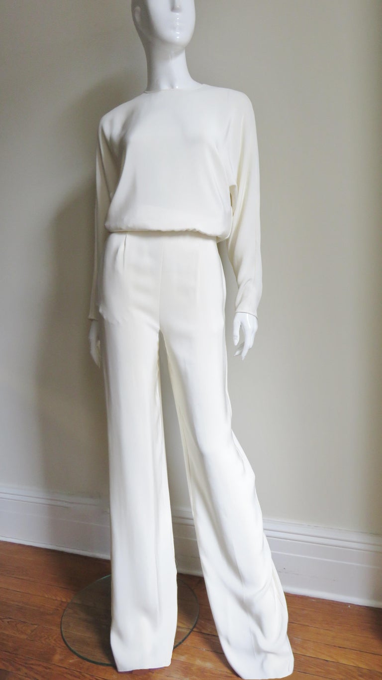 A fabulous off white silk jumpsuit by Valentino.  It has a crew neckline, blouson bodice, dolman sleeves with zipper wrists, full legs and an open slit from the neck to the waist in the back.  It is fully lined in off white silk and has side seam
