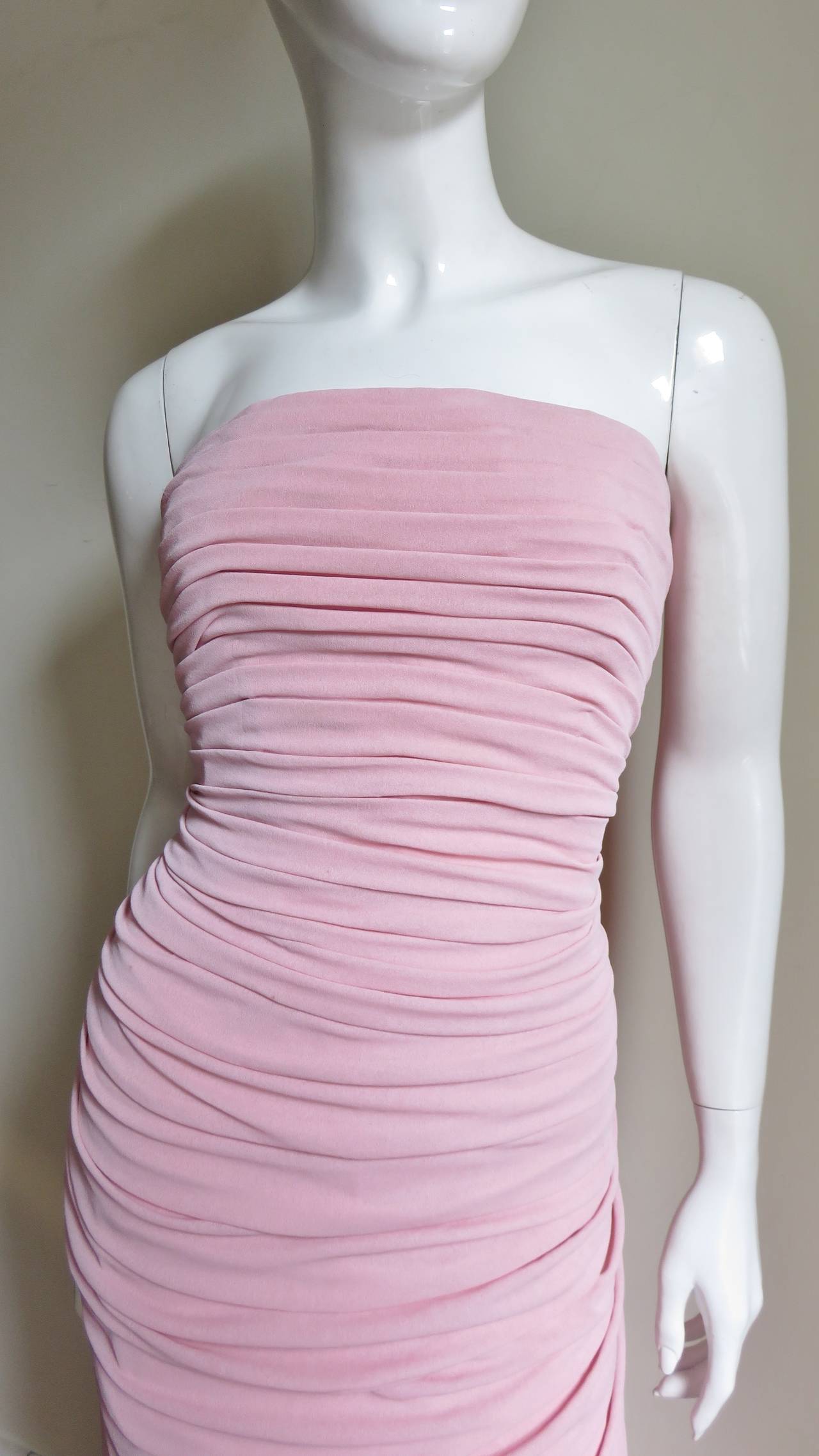 A stunning glamorous strapless column gown in pink silk from Louis Estevez.  It is luxurious with horizontal ruching draping from side to side the front length of the dress and in angles to the back waist then falling full towards the hem. There is