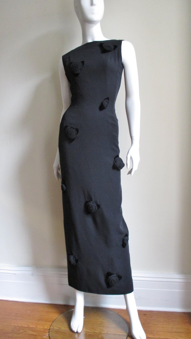 A fabulous long black gown covered in black rose appliques from Estevez.  It is sleeveless with a low scoop back and is covered in elaborately constructed roses comprised of fabric petals and velvet leaves.  Stunning.  It is lined in black silk, has