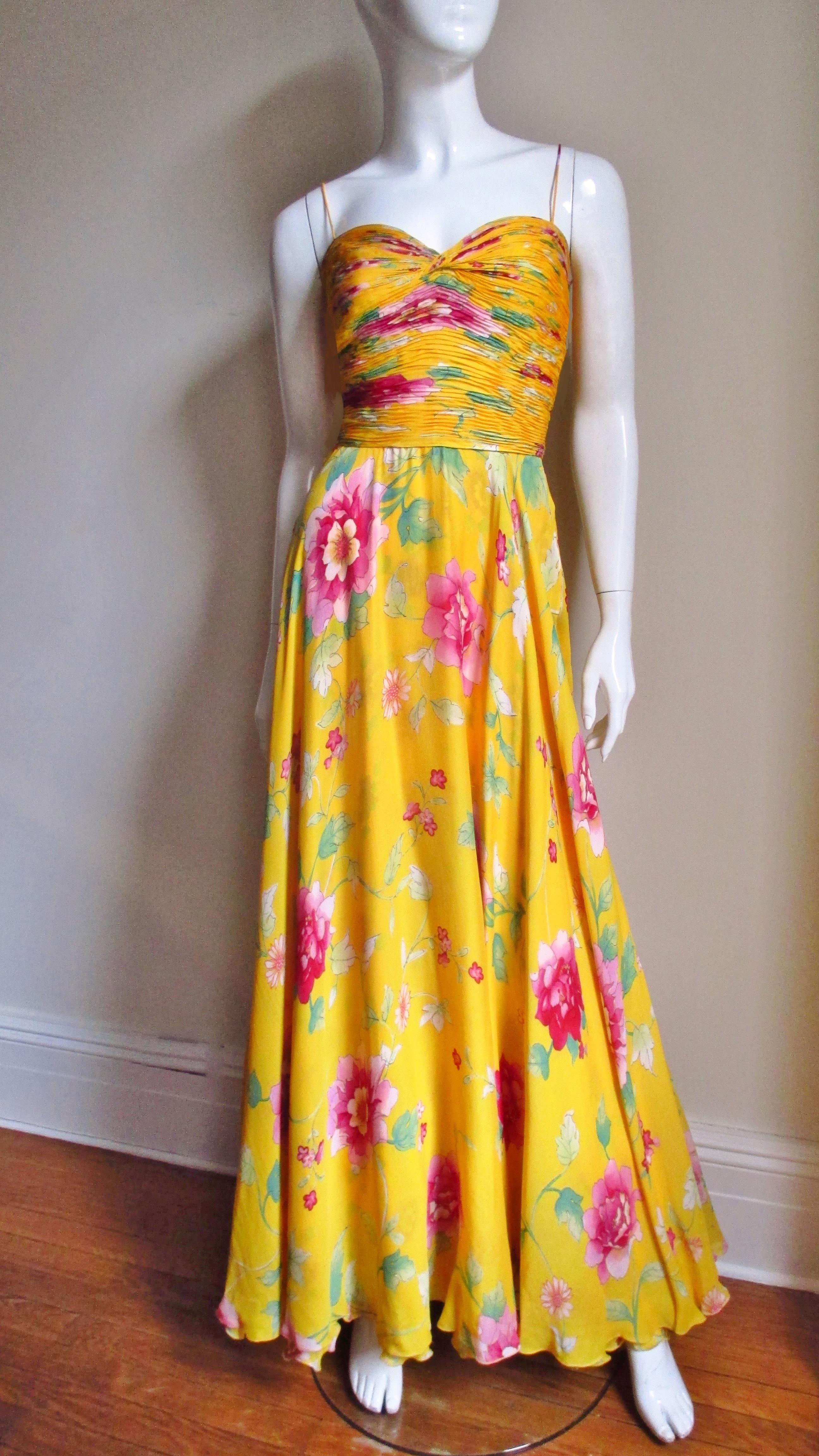 A beautiful marigold yellow silk dress from Valentino's 2006 Spring/ Summer Collection with a pink and green flower pattern.  The sweetheart bodice has spagehtti straps and is horizontally ruched front and back.  The skirt is simple flaring towards