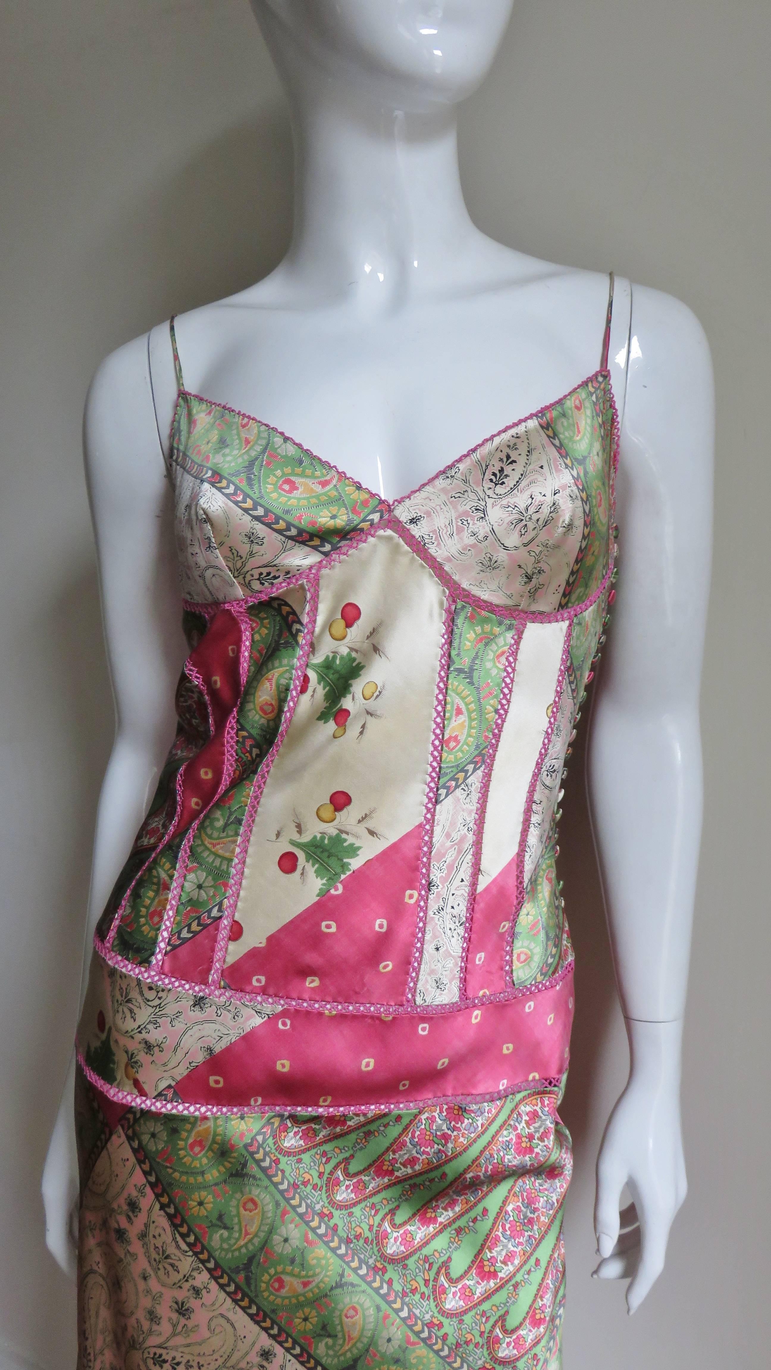 A gorgeous silk charmeuse dress from John Galliano for Christian Dior in a pink, green and soft gold pattern of elaborate paisleys and abstract shapes. The slip style dress has spaghetti straps and a highlighted vertical seamed bodice. The skirt