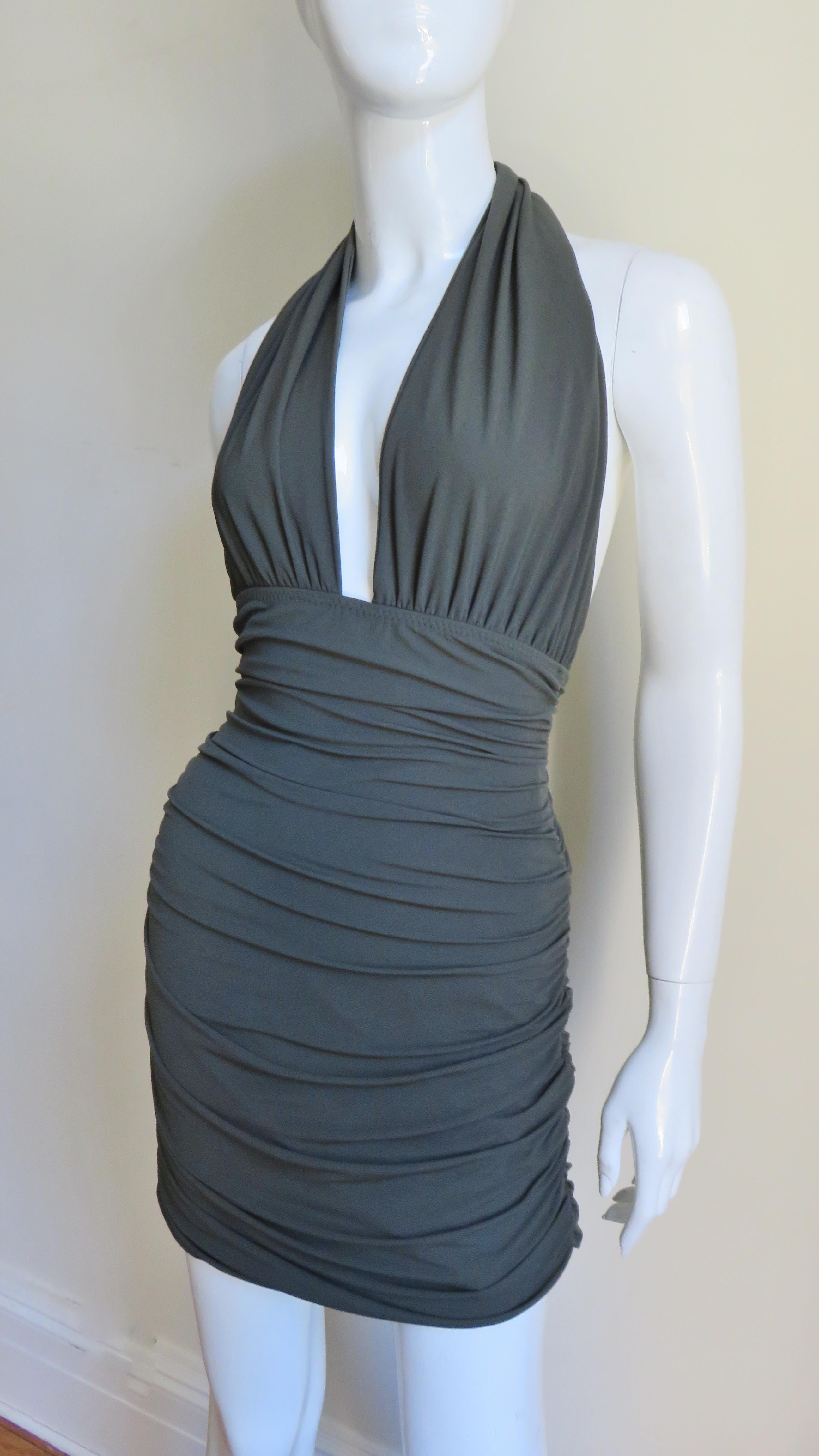 A great olive green jersey halter dress by Norma Kamali.  It has a plunging neckline with a horizontally gathered bust, bare back and a horizontally ruched skirt front and back. It is lined in the same fabric and slips on.  
Fits sizes Extra Small,