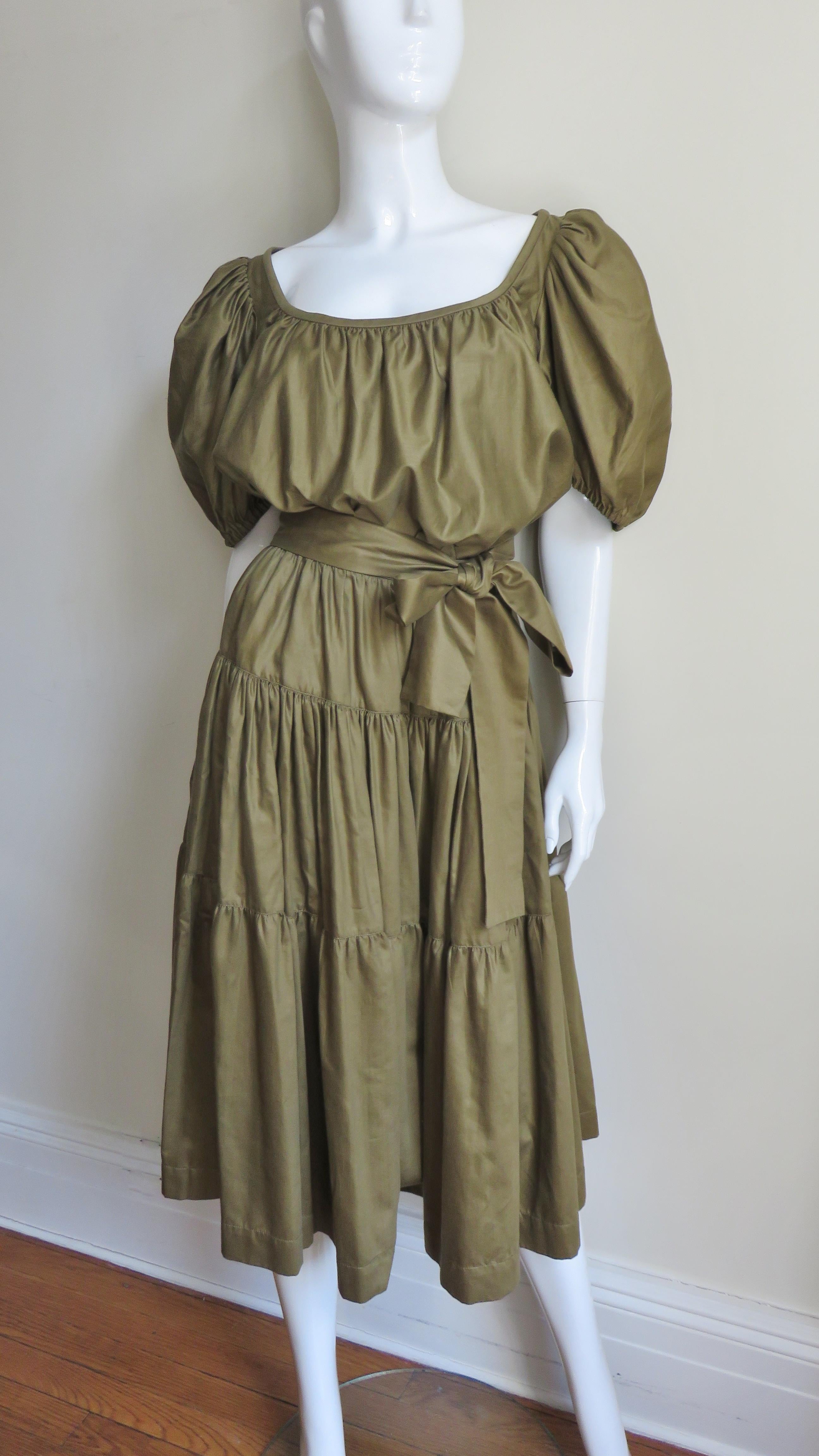 A fabulous olive green polished cotton 1960s top and skirt from YSL Yves St Laurent Rive Gauche.  The peasant style blouse has gathered puff sleeves and a gathered neckline to be worn on or off the shoulders. The full skirt consists of 3 gathered