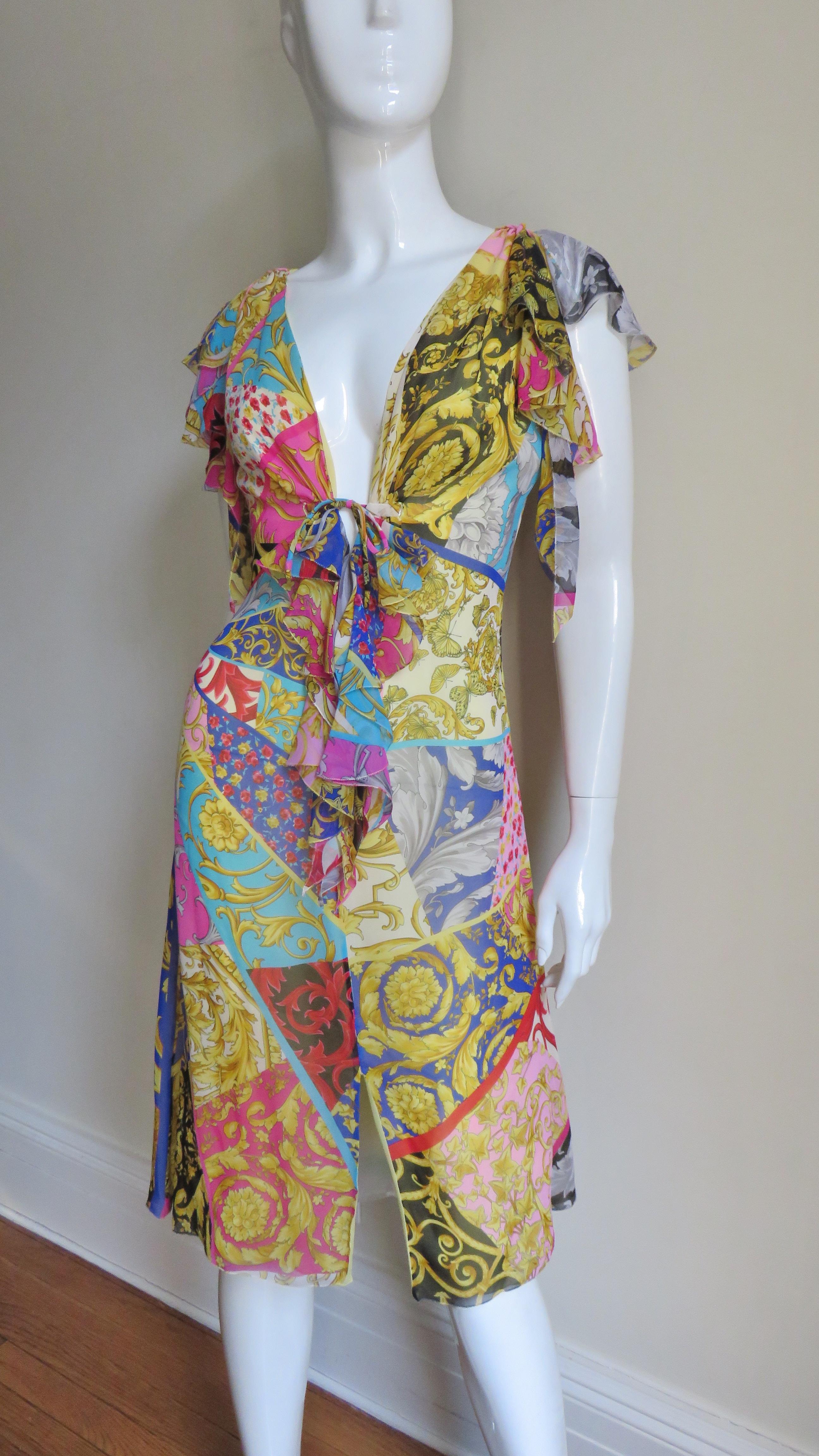 A fabulous silk dress from Gianni Versace in a compilation patchwork of some of his most notable colorful prints including scrolls, feathers and flowers.  It is sleeveless and has a plunging neckline with a tie below the bust, draping around the