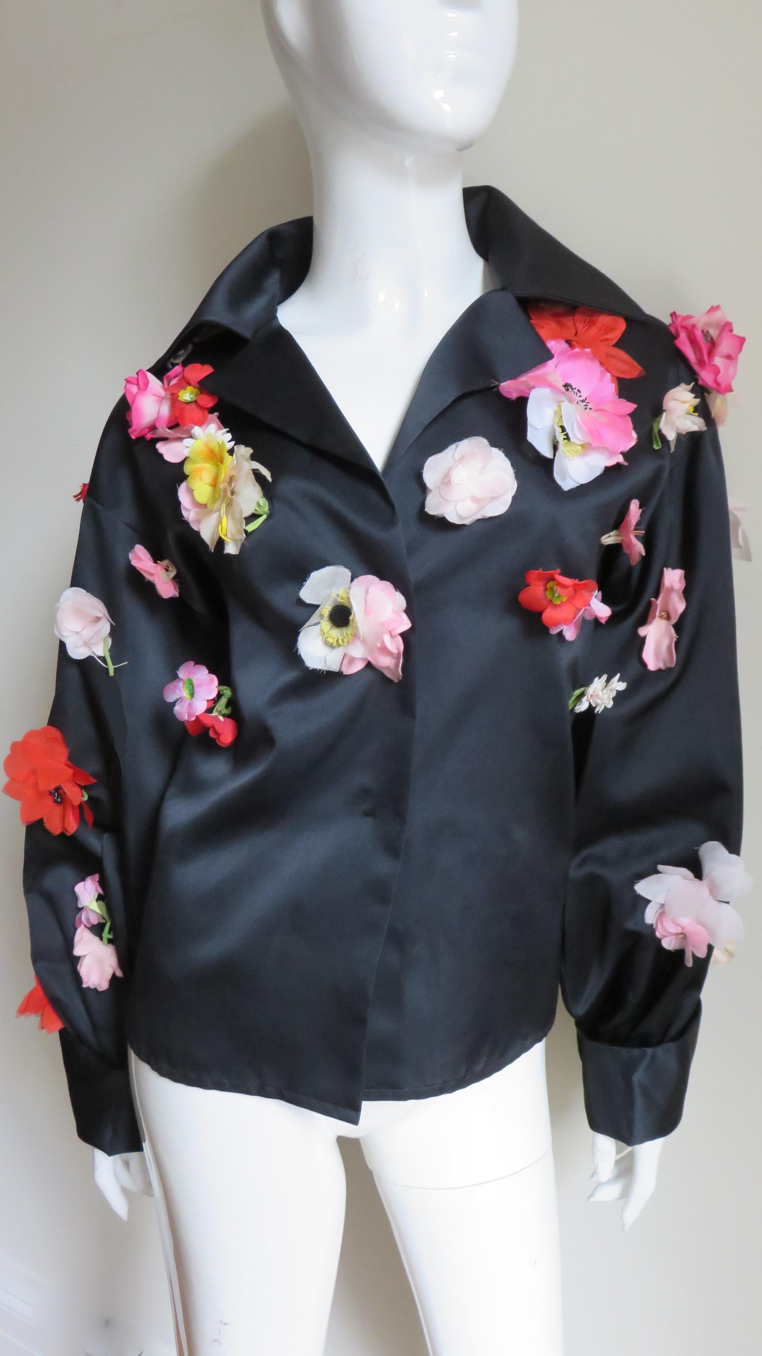 An incredible black silk shirt, blouse, jacket from Bill Blass  It has a lapel collar and full sleeves with fold back cuffs.  The jacket is covered in hand made silk flower appliques of varying types, sizes and colors. Stunning!  It has black silk