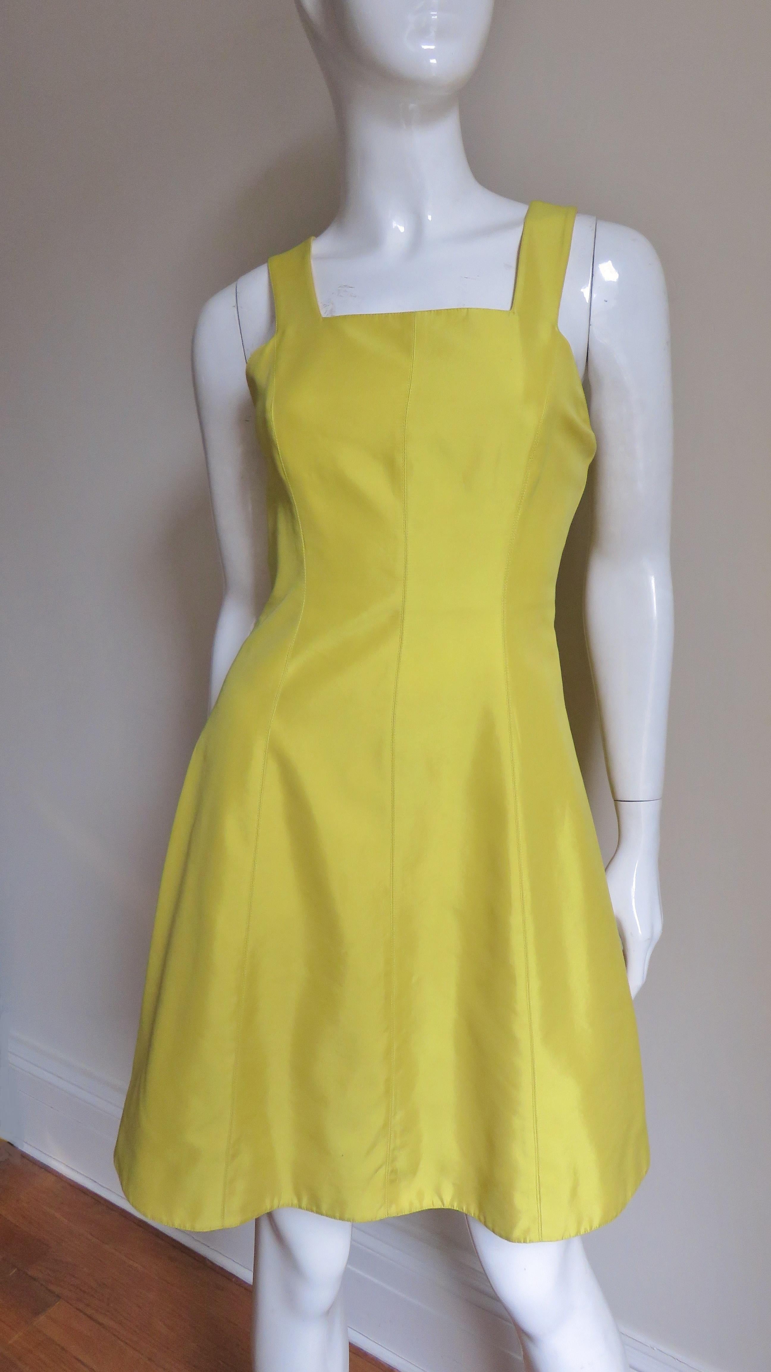 A beautiful yellow silk dress from Claude Montana. It has a square neckline, princess seaming for a great fit and an A line skirt. The back shoulder straps meet a band mid level with a cutout beneath.  It has matching silk lining, a matching back