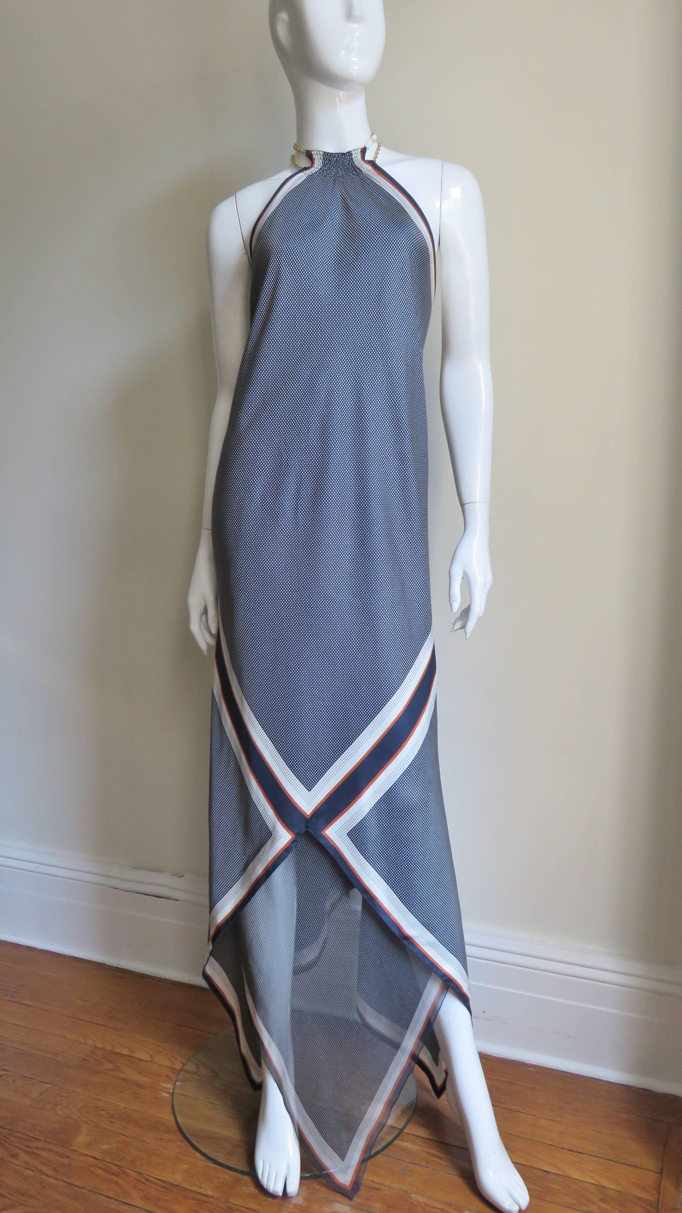 A fabulous silk dress in navy with white dots trimmed in white and rust stripes.  The dress drapes beautifully on the body and has a ruched halter with delicate chains, small white leather straps and buckles closing at the neck.  A sheer panel of